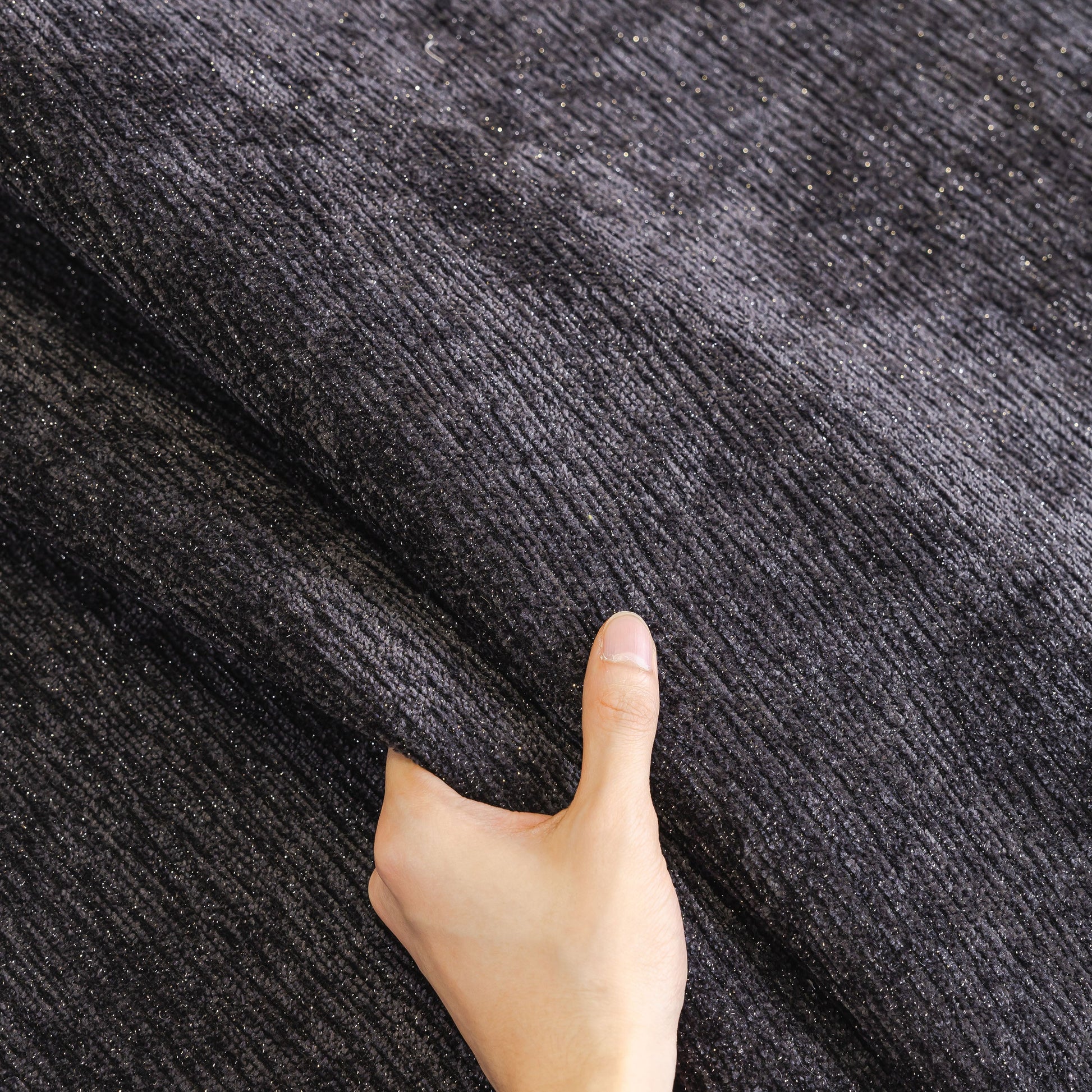 Hand touching black chenille fabric of Chenille Couch Cover with Scalloped Edge, Non-Slip Modular Slipcover Sectional