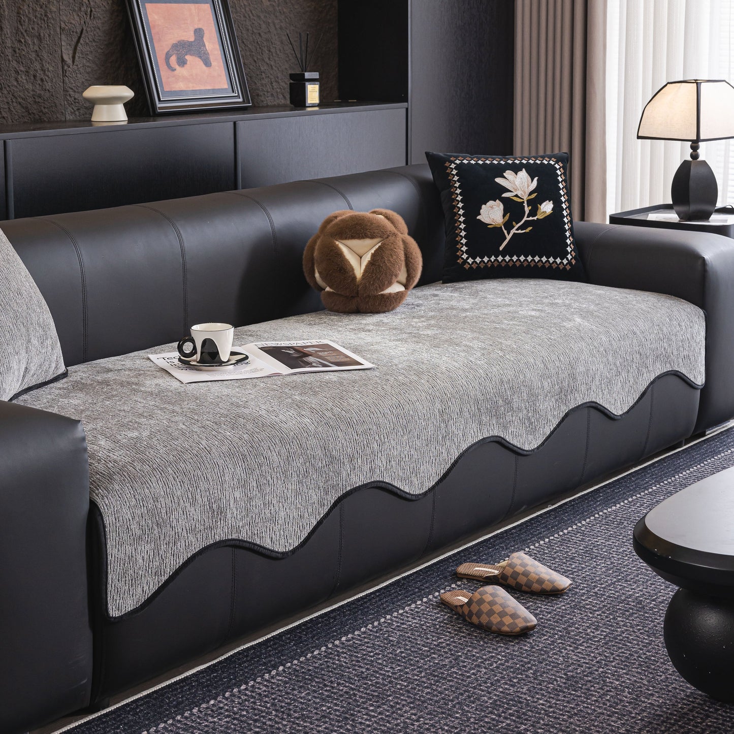 Chenille Couch Cover with Scalloped Edge, Non-Slip Modular Slipcover on black leather sofa with decorative cushions.