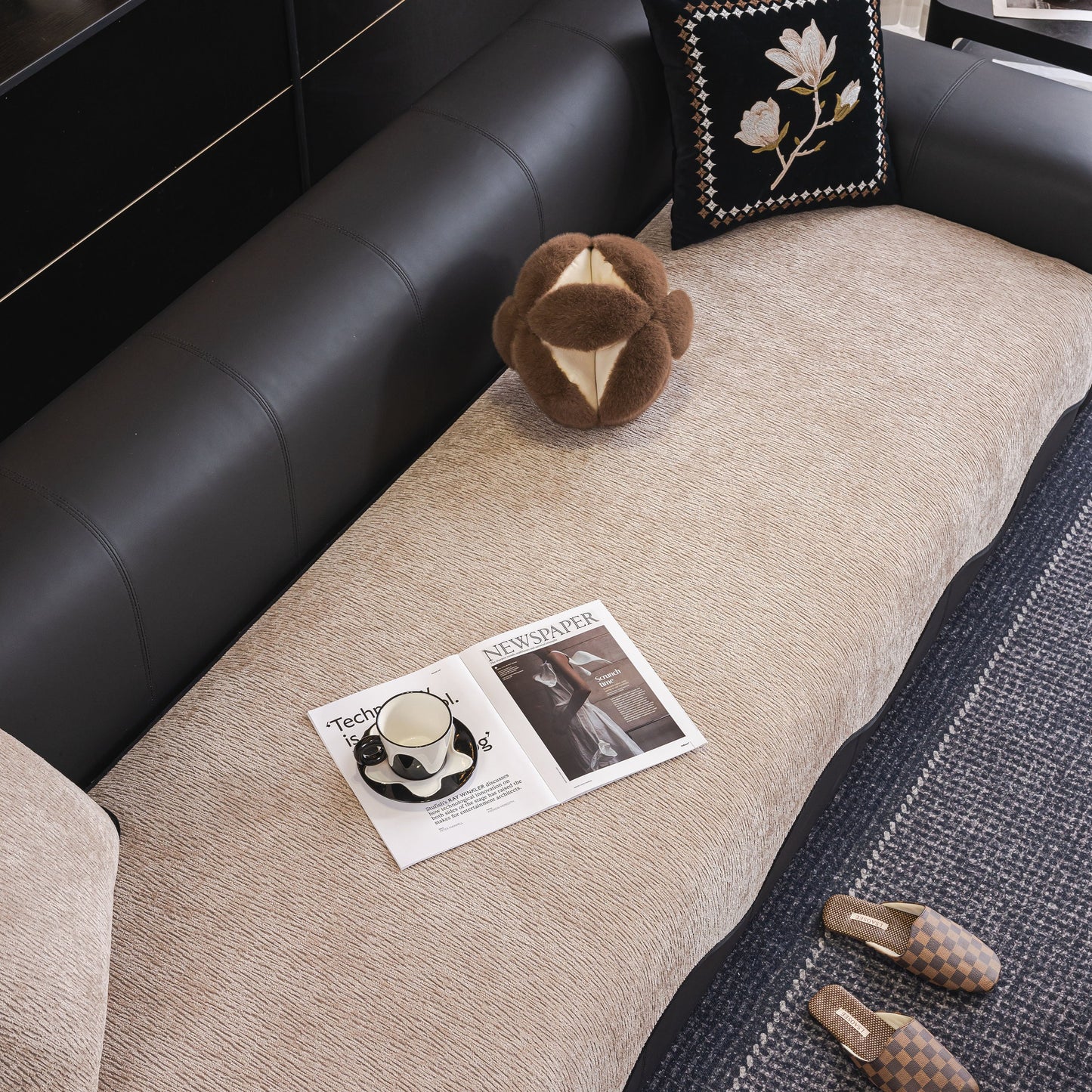 Chenille Couch Cover with Scalloped Edge, Non-Slip Modular Slipcover Sectional on a black leather sofa with pillows and slippers.