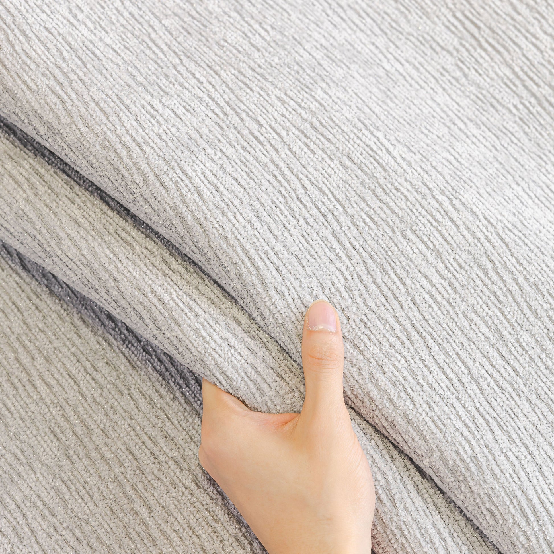 Hand touching the soft texture of Chenille Couch Cover with Scalloped Edge, Non-Slip Modular Slipcover Sectional