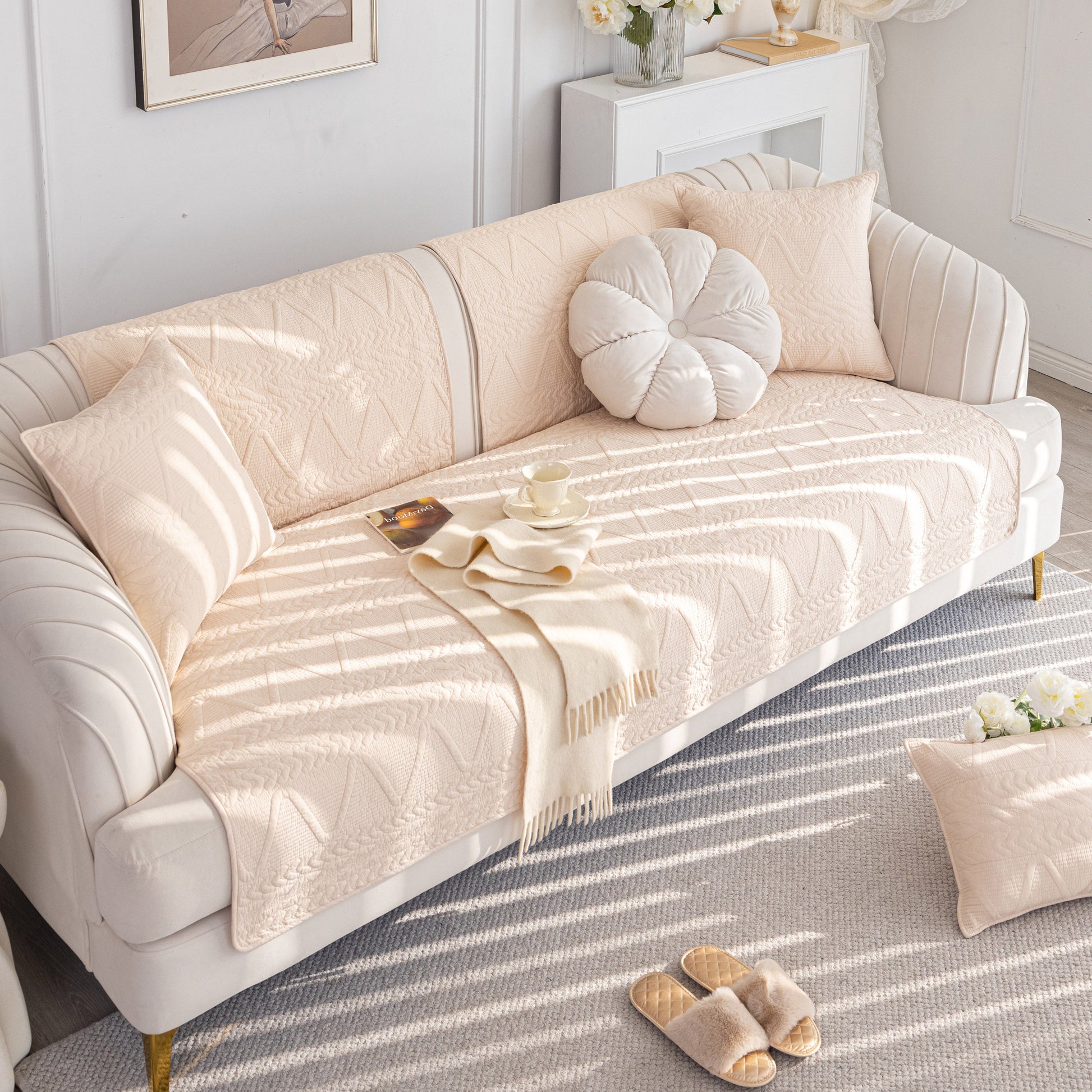 Beige Geometric Textured Cotton Quilted Sofa Cover, Non-Slip Washable Couch Protector on a white sofa with pillows and a throw.
