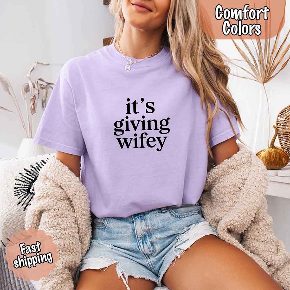 Woman wearing Its Giving Wifey Comfort Colors Tee, lilac shirt, ideal for brides, wedding, or engagement gift. Fast shipping available.