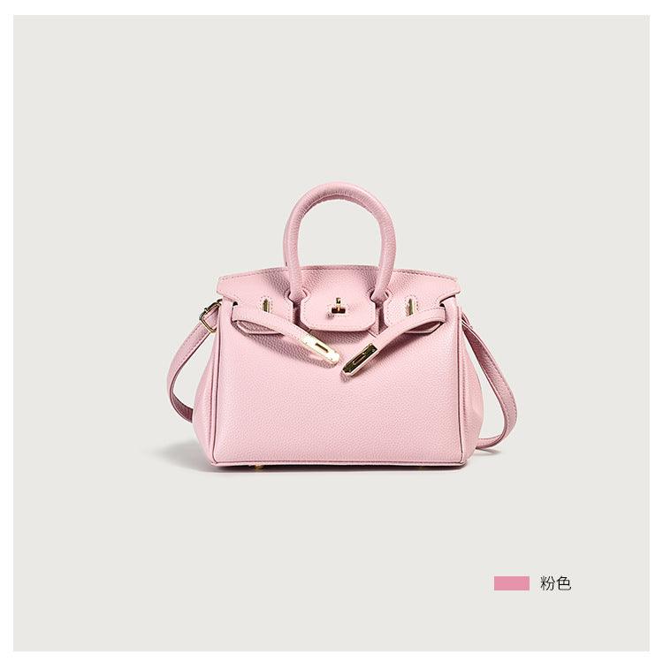 Stylish light pink handbag with gold accents on a neutral background
