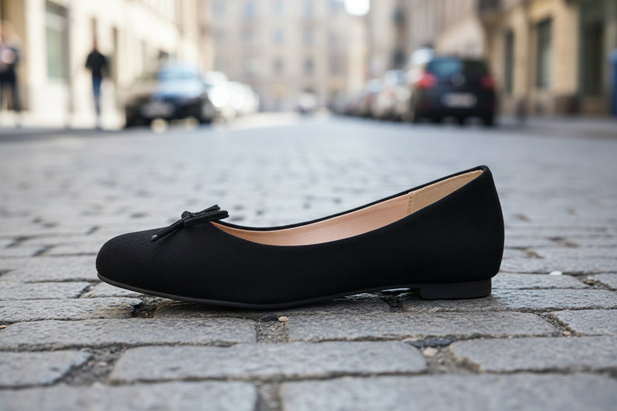 Black ballet flat shoe on urban street background, showcasing minimalist design and casual style.