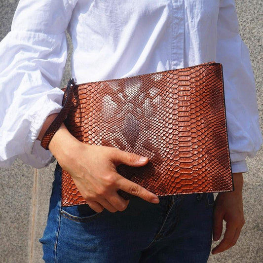 Python Luxe Clutch - Stylish Simulated Leather Clutch for Sophisticated Women with elegant python print held by a person in white blouse.