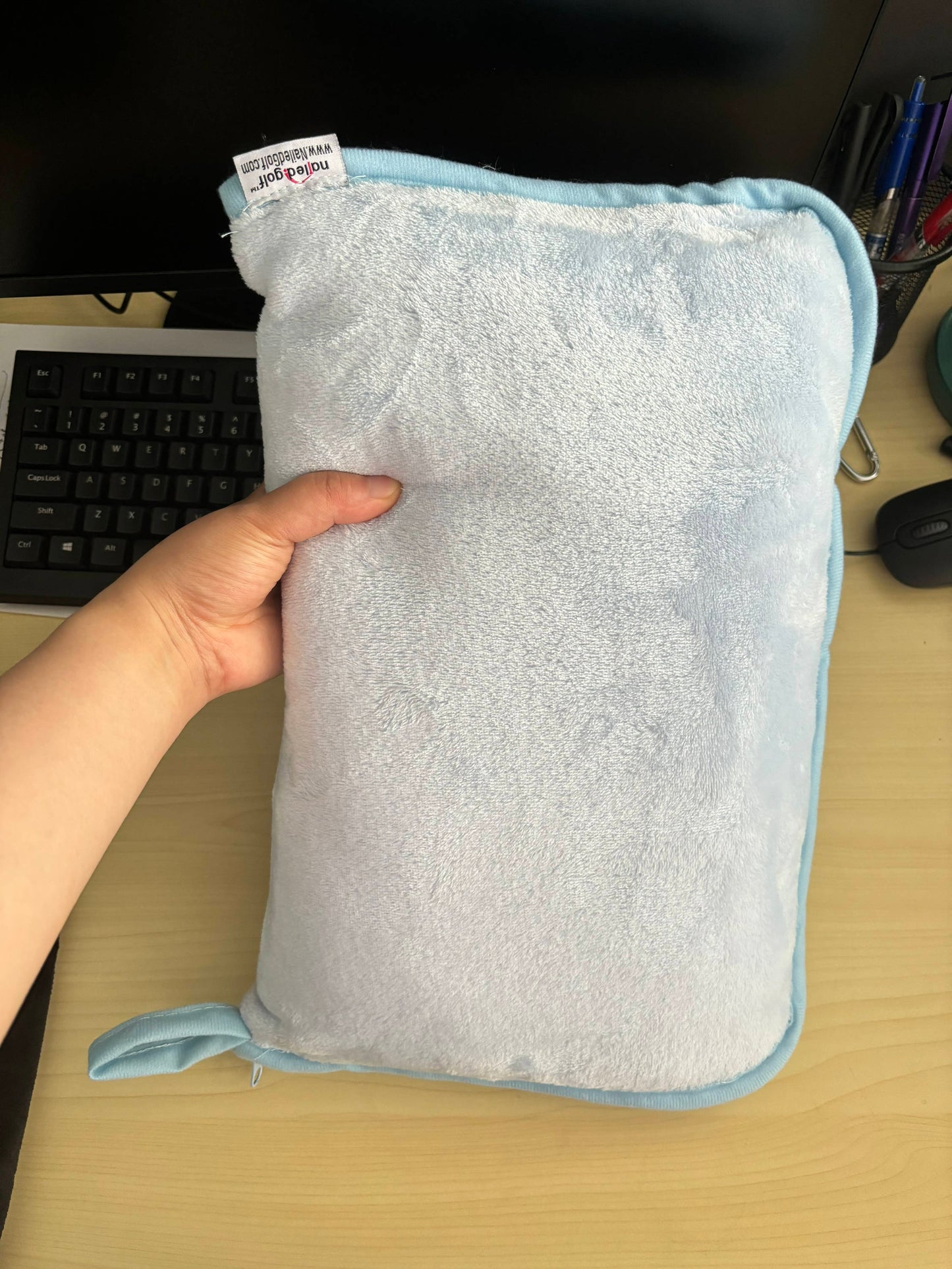 Person holding plush blue Golf / Travel Blanket in matching case for easy storage and travel convenience.
