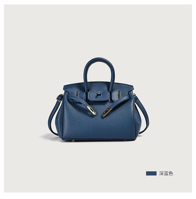 Blue leather handbag with gold accents on a plain background