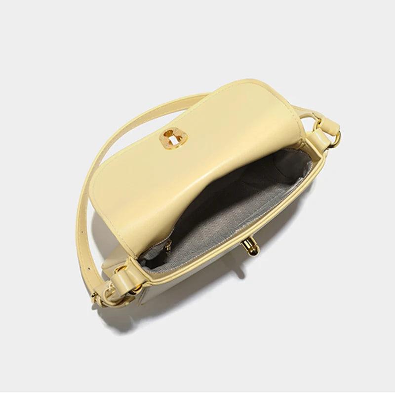 Cream leather handbag with open flap showing interior, gold hardware detail. Modern design with adjustable strap, showcasing practical luxury.