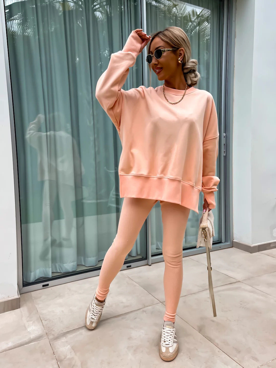 Woman wearing Women’s Casual Sweater Suit – Loose Split Top & Fitted Trousers Set in peach, standing on patio.