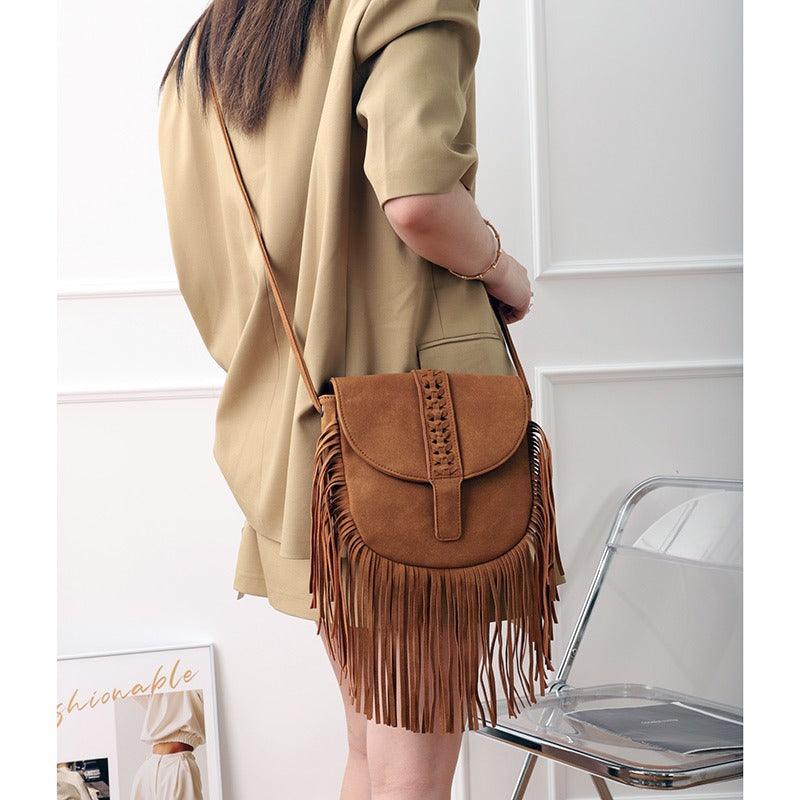Woman holding Dakota Tasseled Boho Leather Bag, a trendy large tassel shoulder bag with intricate weaving and boho-chic style.