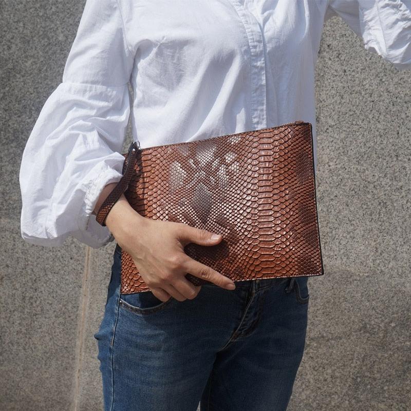 Woman holding Python Luxe Clutch - Stylish Simulated Leather Clutch for Sophisticated Women with elegant python print