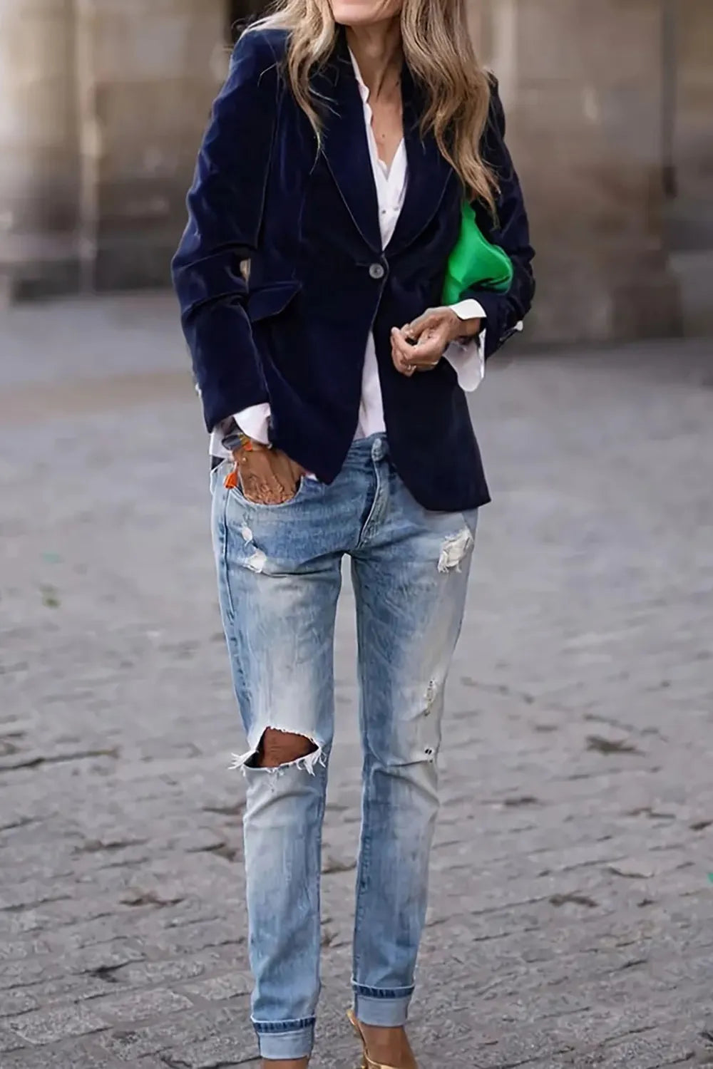 Woman wearing a One-Button Lapel Collar Long Sleeve Blazer for Women with jeans and holding a green clutch on the street.