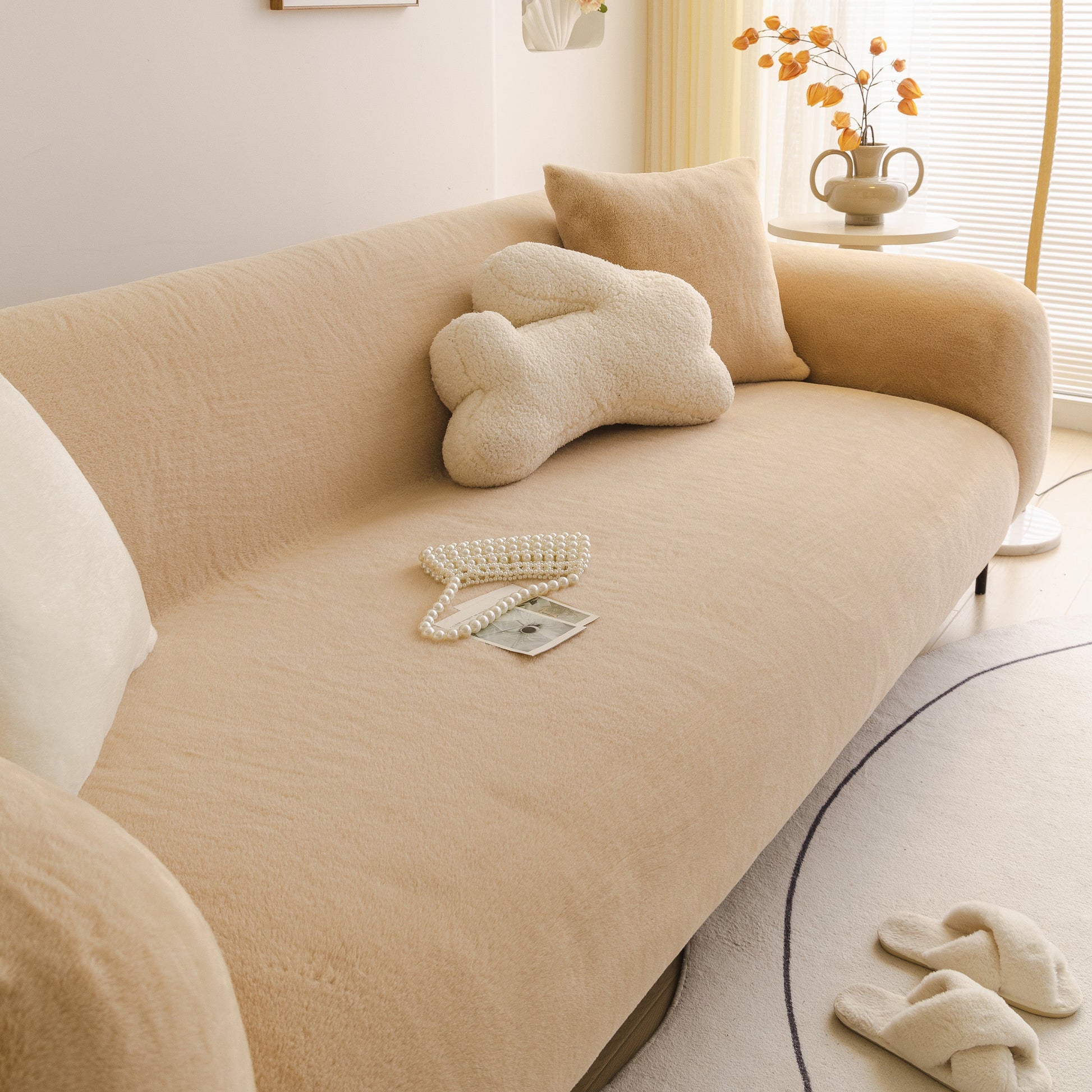 Cream soft plush warm sofa cover stretchable cozy velvet couch protector for fall & winter on a modern living room sofa.