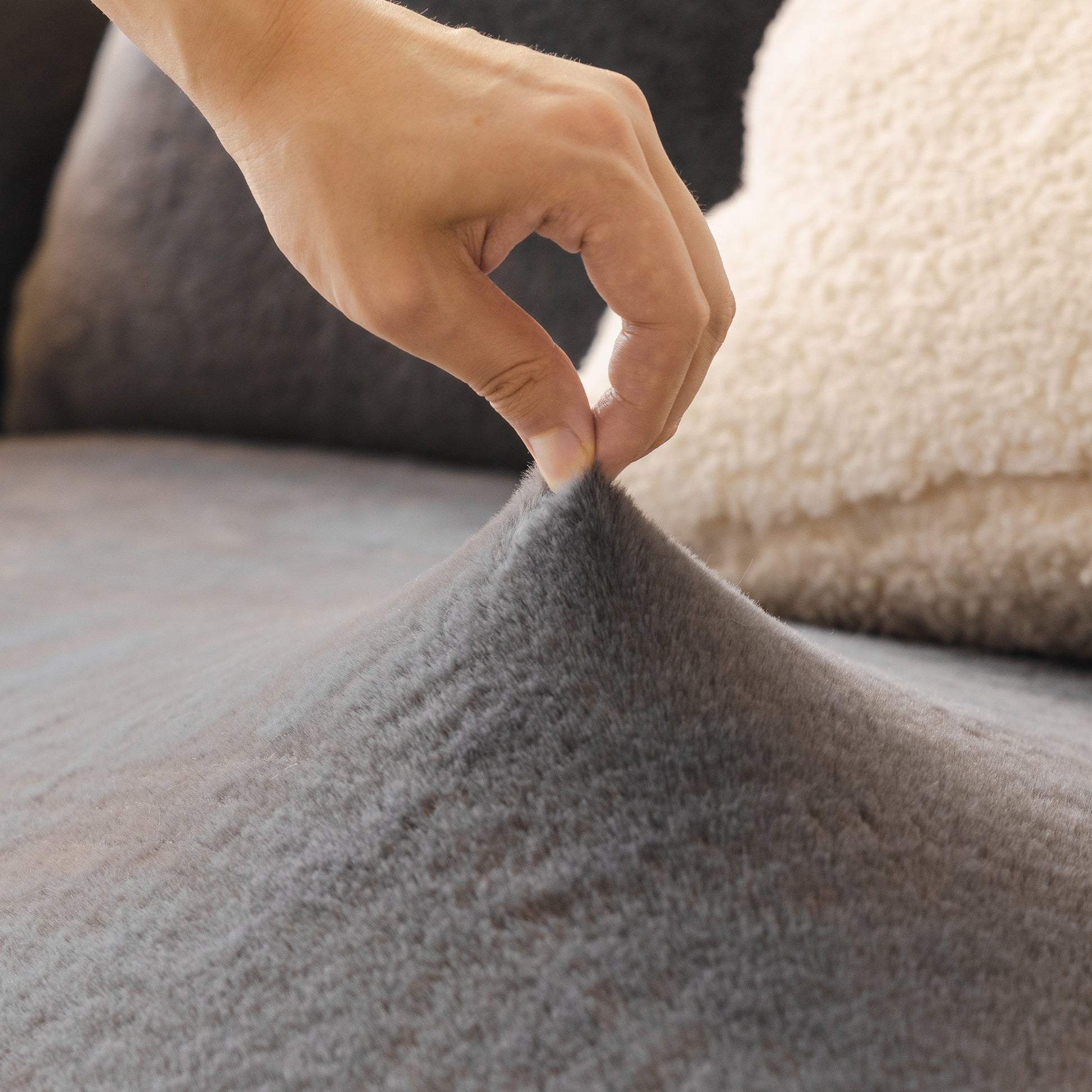 Hand testing stretchability of Soft Plush Warm Sofa Cover Stretchable Cozy Velvet Couch Protector for Fall & Winter on a couch.