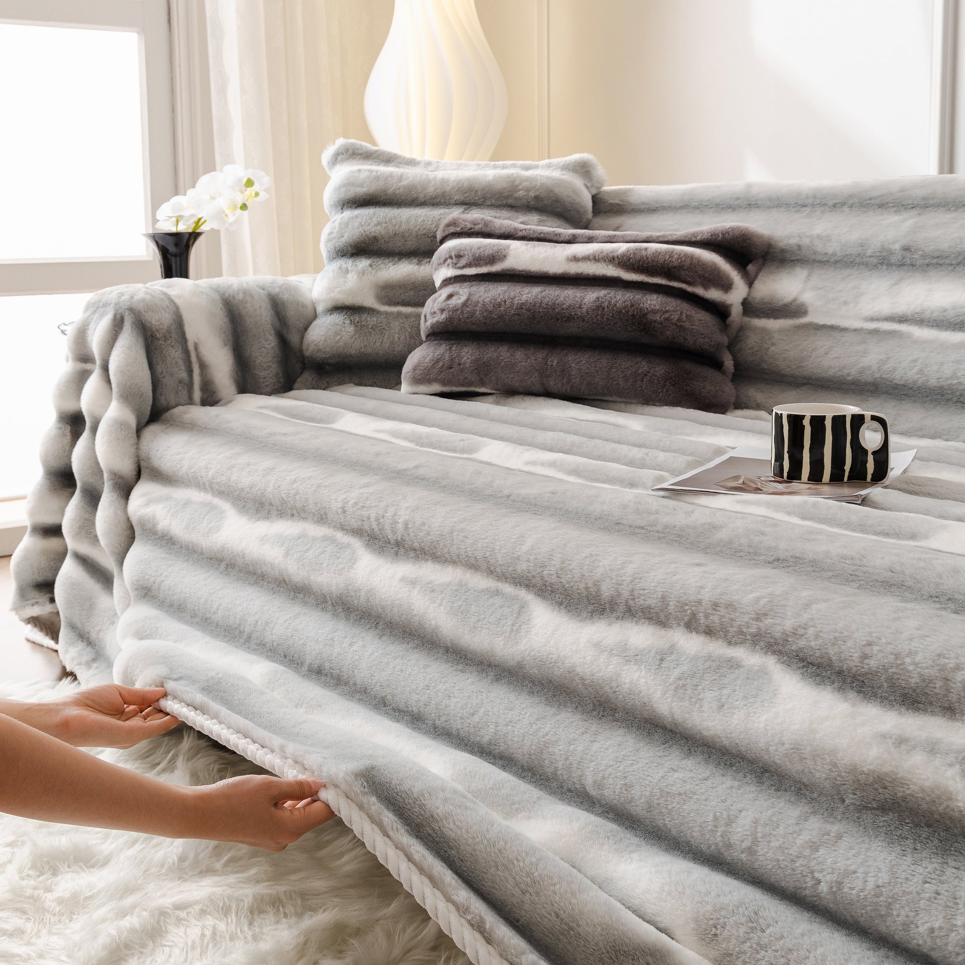Ultra Soft Faux Fur Couch Cover – Large, Fluffy, and Elegant Sofa Throw Blanket on a modern sofa with a cup and stacked pillows.