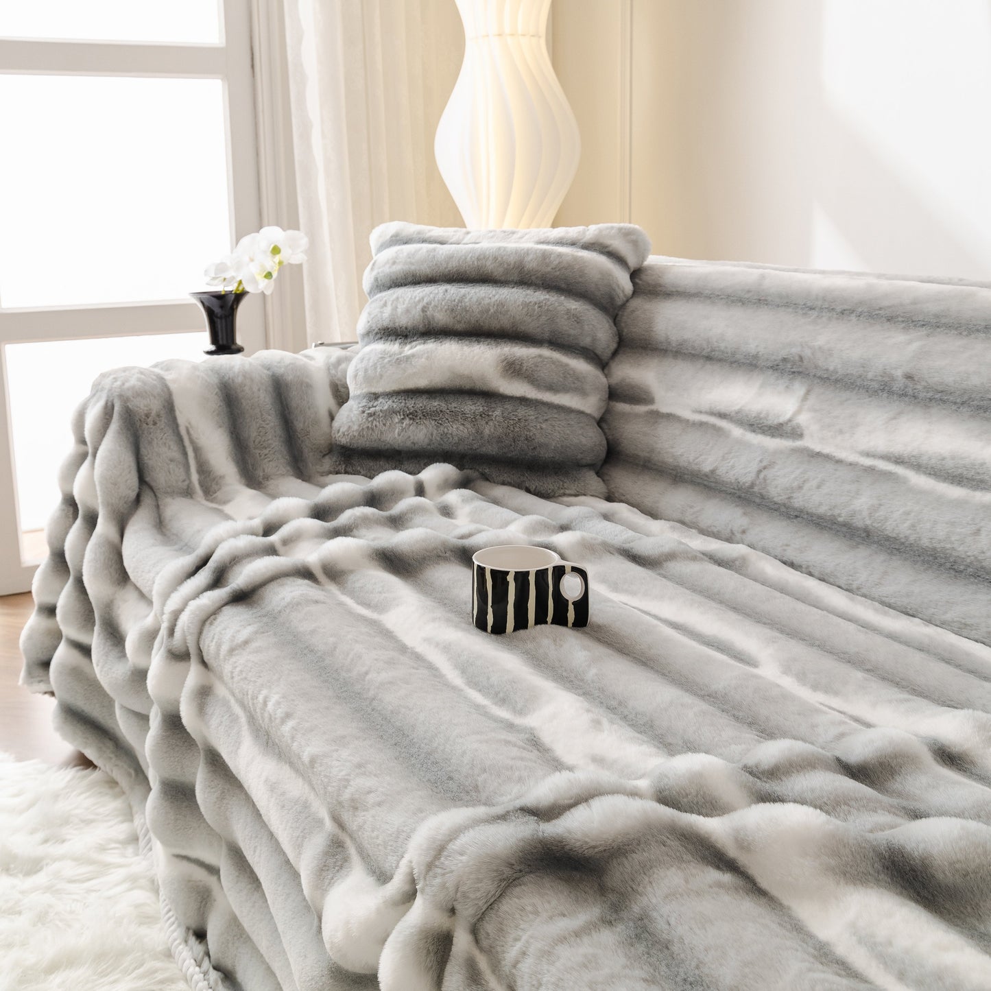 Ultra Soft Faux Fur Couch Cover – Large, Fluffy, and Elegant Sofa Throw Blanket draped over a stylish sofa with a mug on top.