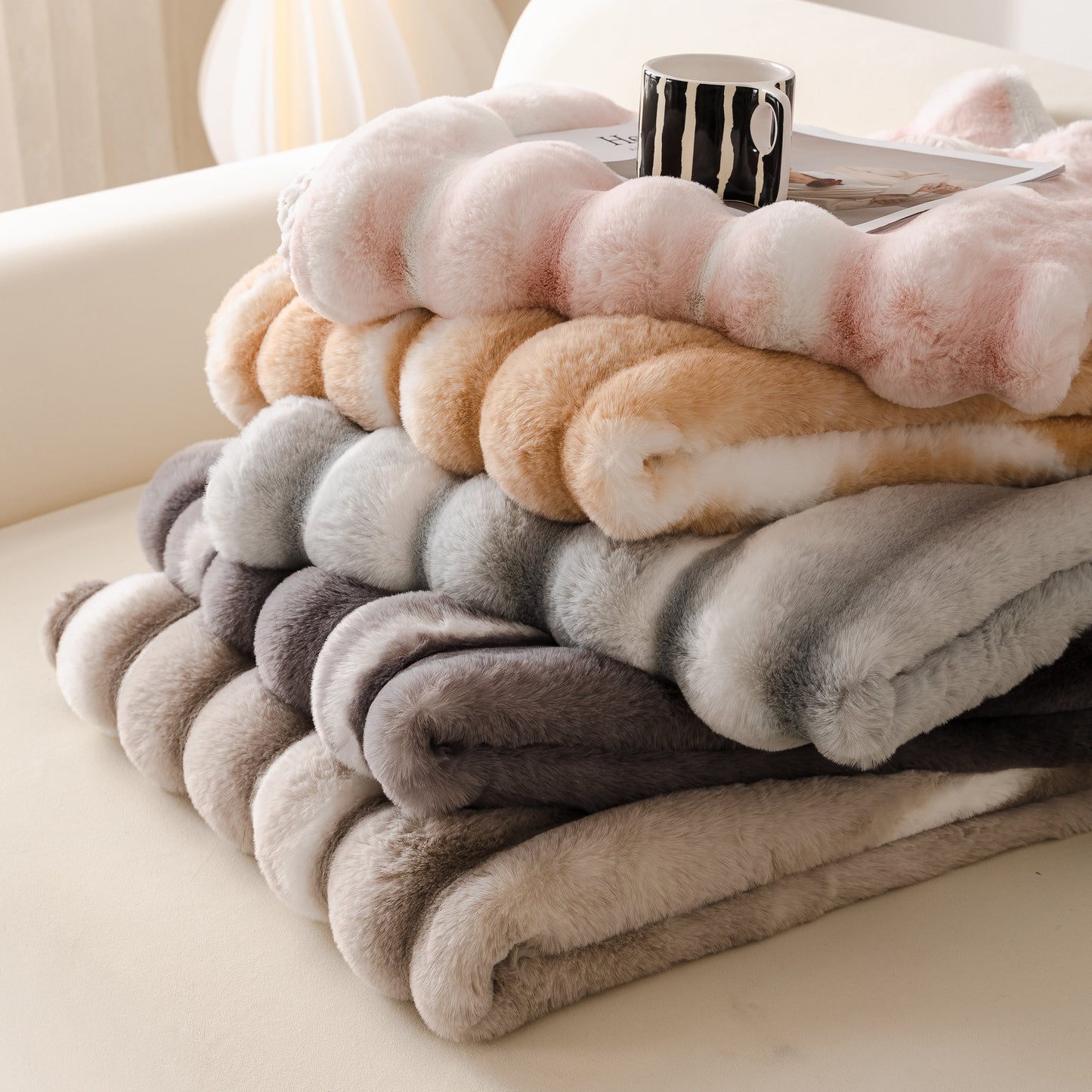 Stack of Ultra Soft Faux Fur Couch Cover – Large, Fluffy, and Elegant Sofa Throw Blanket in gradient colors on a sofa