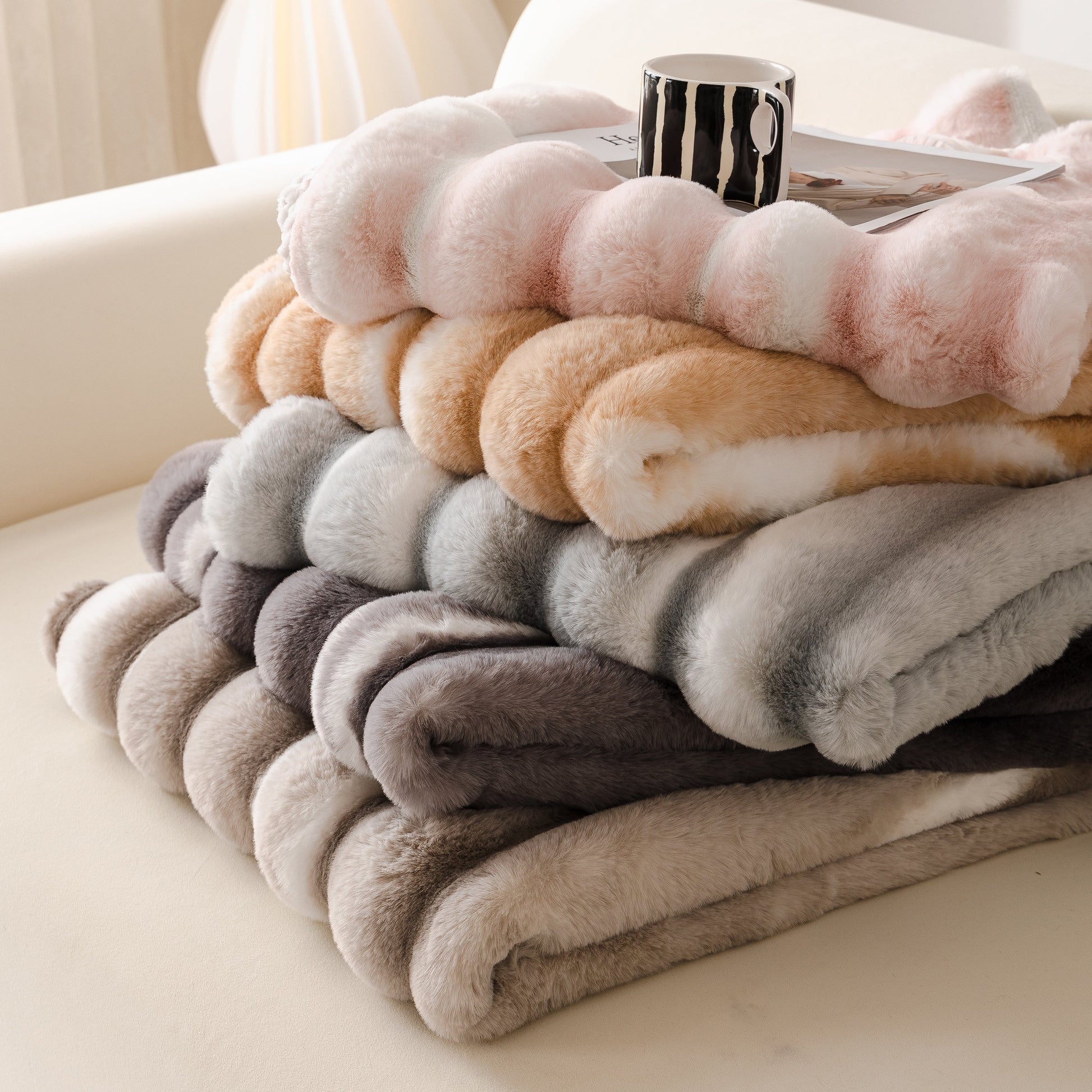 Stack of Ultra Soft Faux Fur Couch Cover – Large, Fluffy, and Elegant Sofa Throw Blanket in gradient colors on a sofa