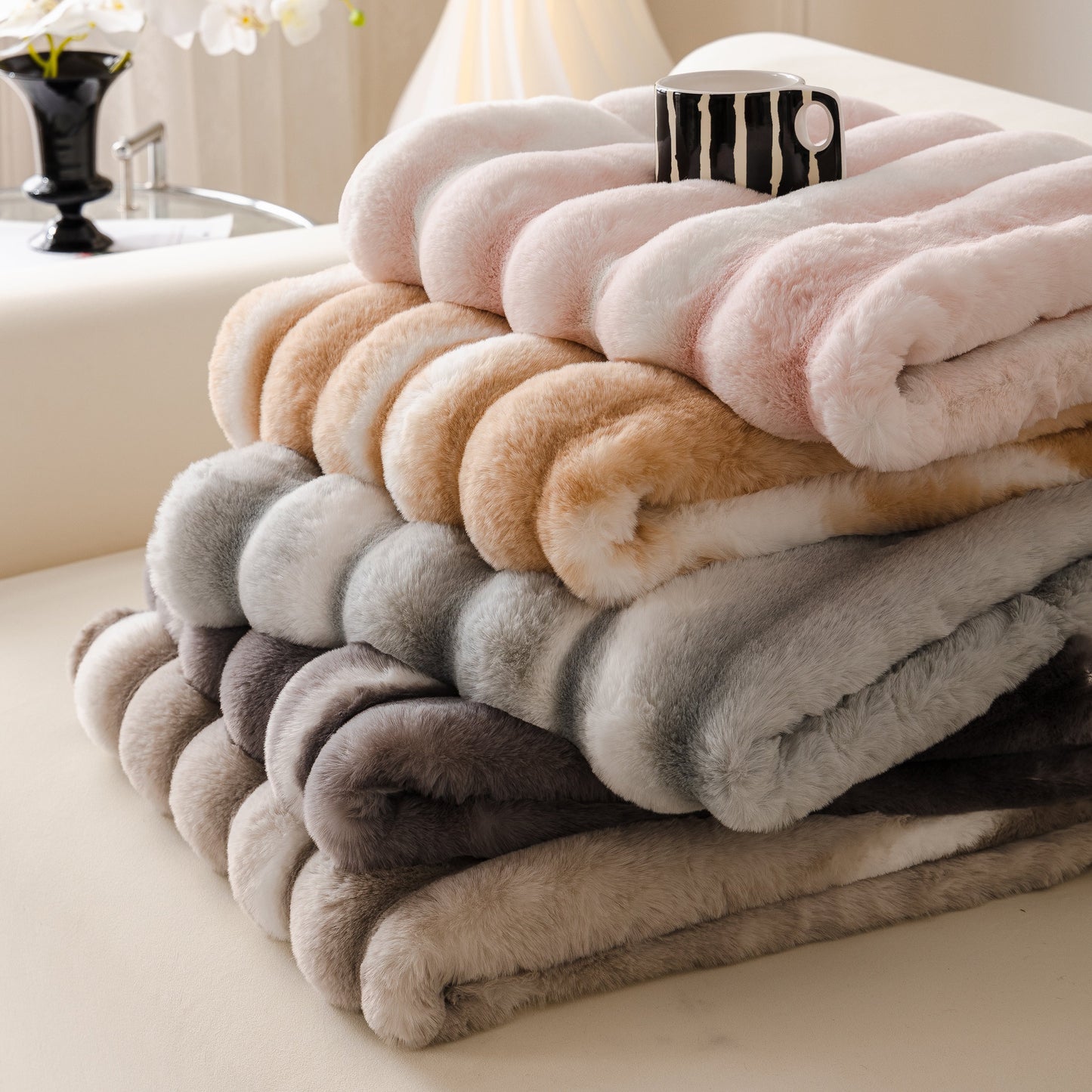 Ultra Soft Faux Fur Couch Cover – Large, Fluffy, and Elegant Sofa Throw Blanket in various colors stacked on a couch.
