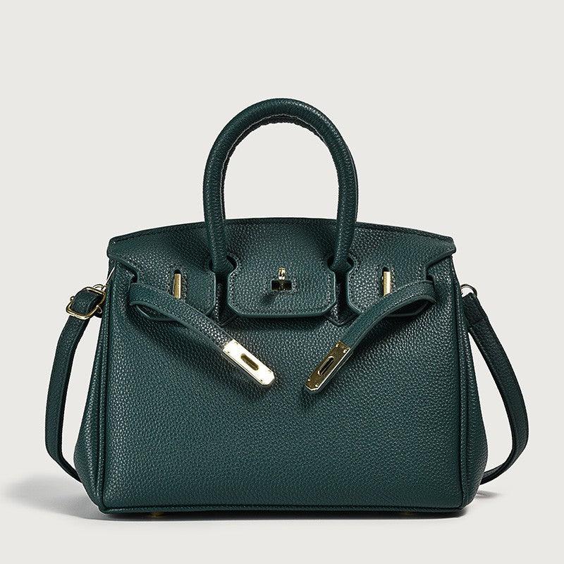 Teal leather handbag with classic design and gold accents on a plain background.