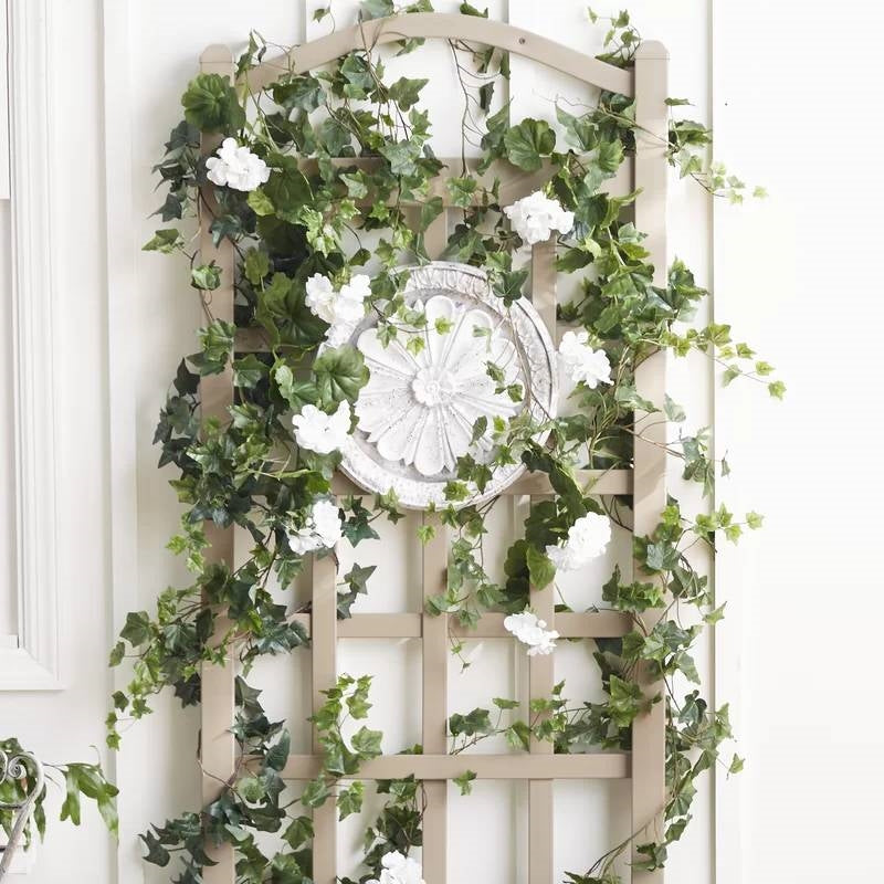 76-inch Tall Mocha Tan Brown Vinyl Garden Trellis with climbing plants and white flowers, enhancing outdoor decor.