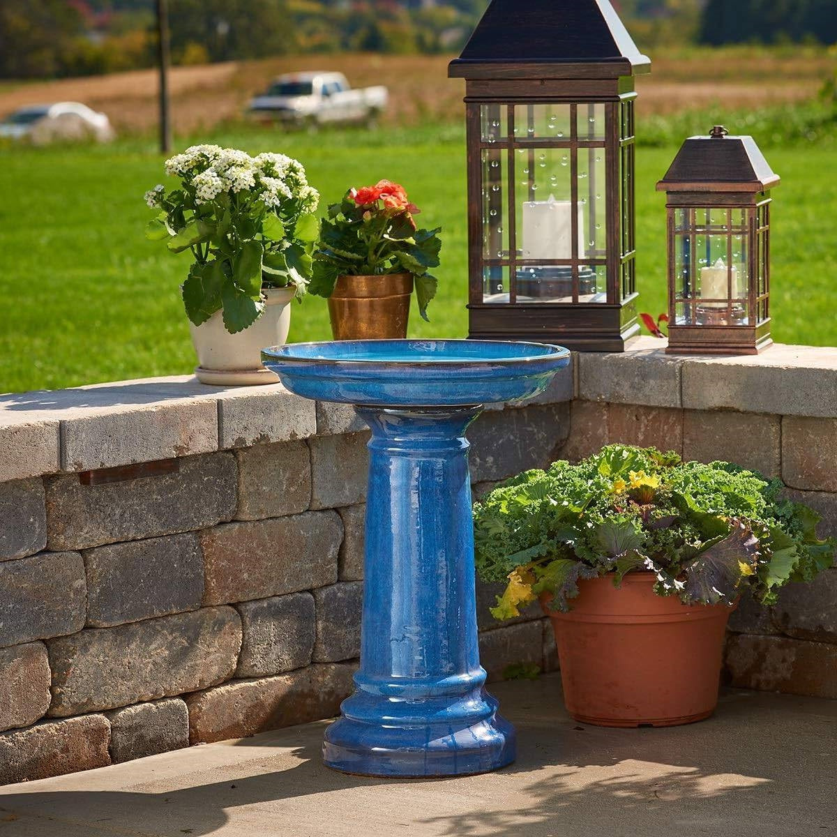 2 Gallon Blue Ceramic Traditional Outdoor Patio Garden Birdbath with plants and lanterns on stone wall