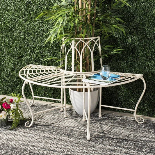 Half-Circle Outdoor Patio Garden Antique White Wrought Iron Tree Bench with scrollwork and greenery background