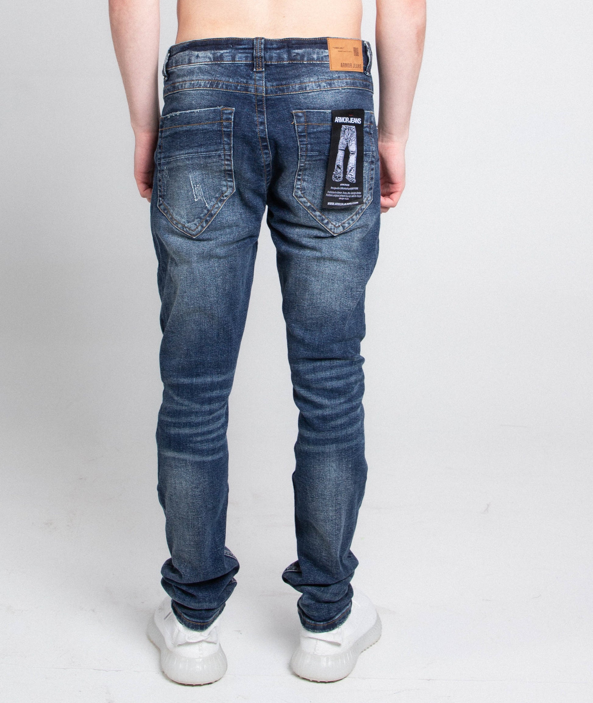 Back view of A403 SMALL RIPPED MID-RISE SKINNY JEANS with five pocket design and belt loops, shown on model wearing white sneakers.