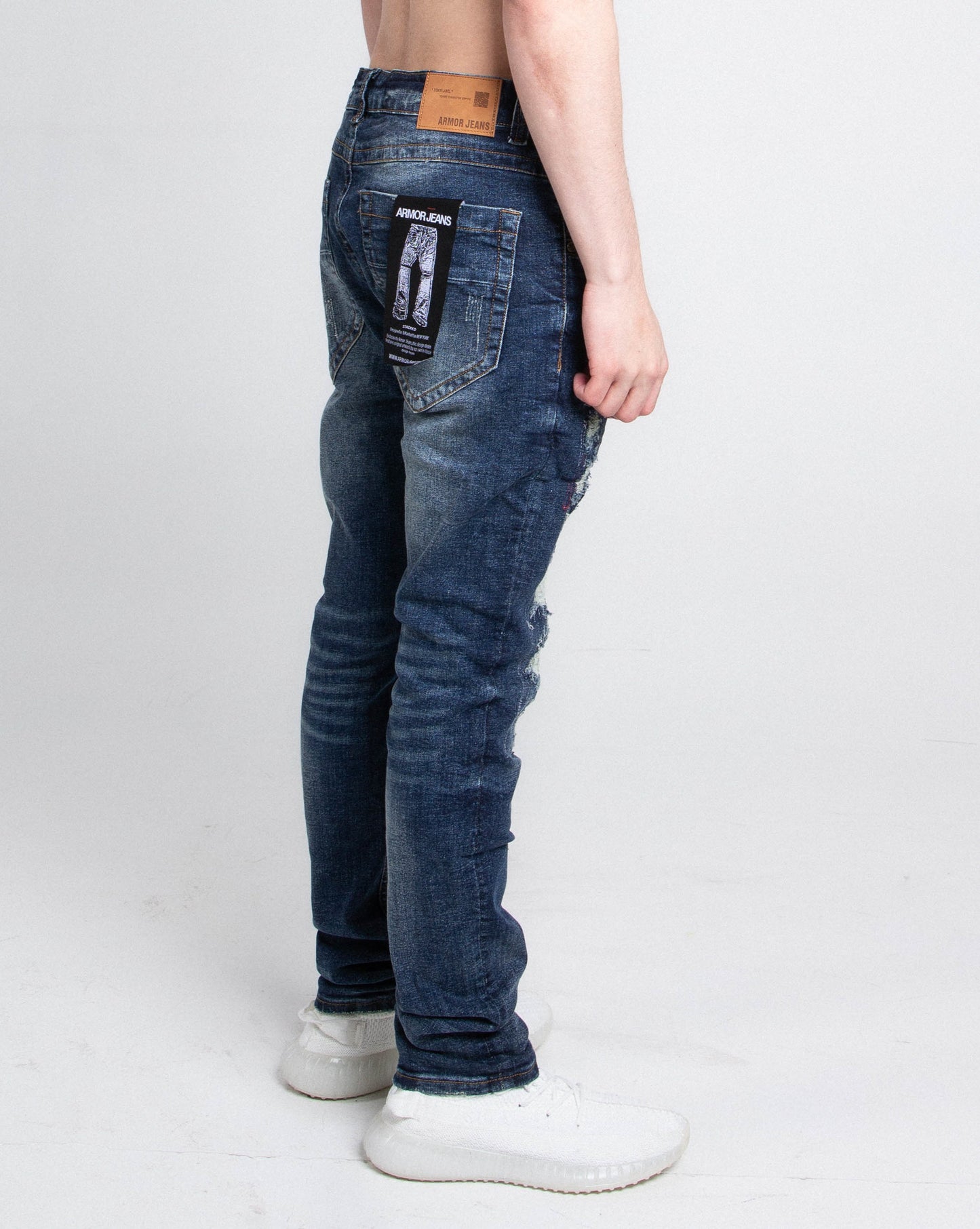 Side view of model wearing A403 SMALL RIPPED MID-RISE SKINNY JEANS with five pockets and a stretchy fabric blend.