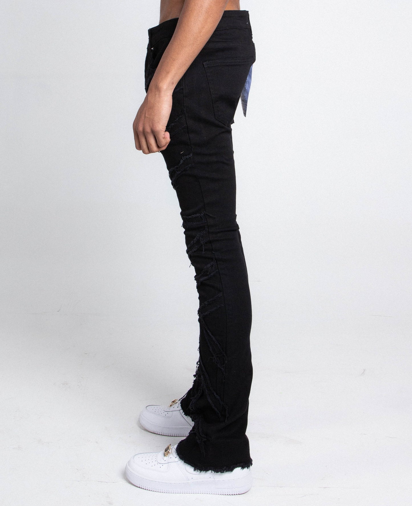 Side view of AJS410 SHREDDED STACKED JEANS in black, featuring a stretchy fabric and mid-rise waist with shredded detailing.