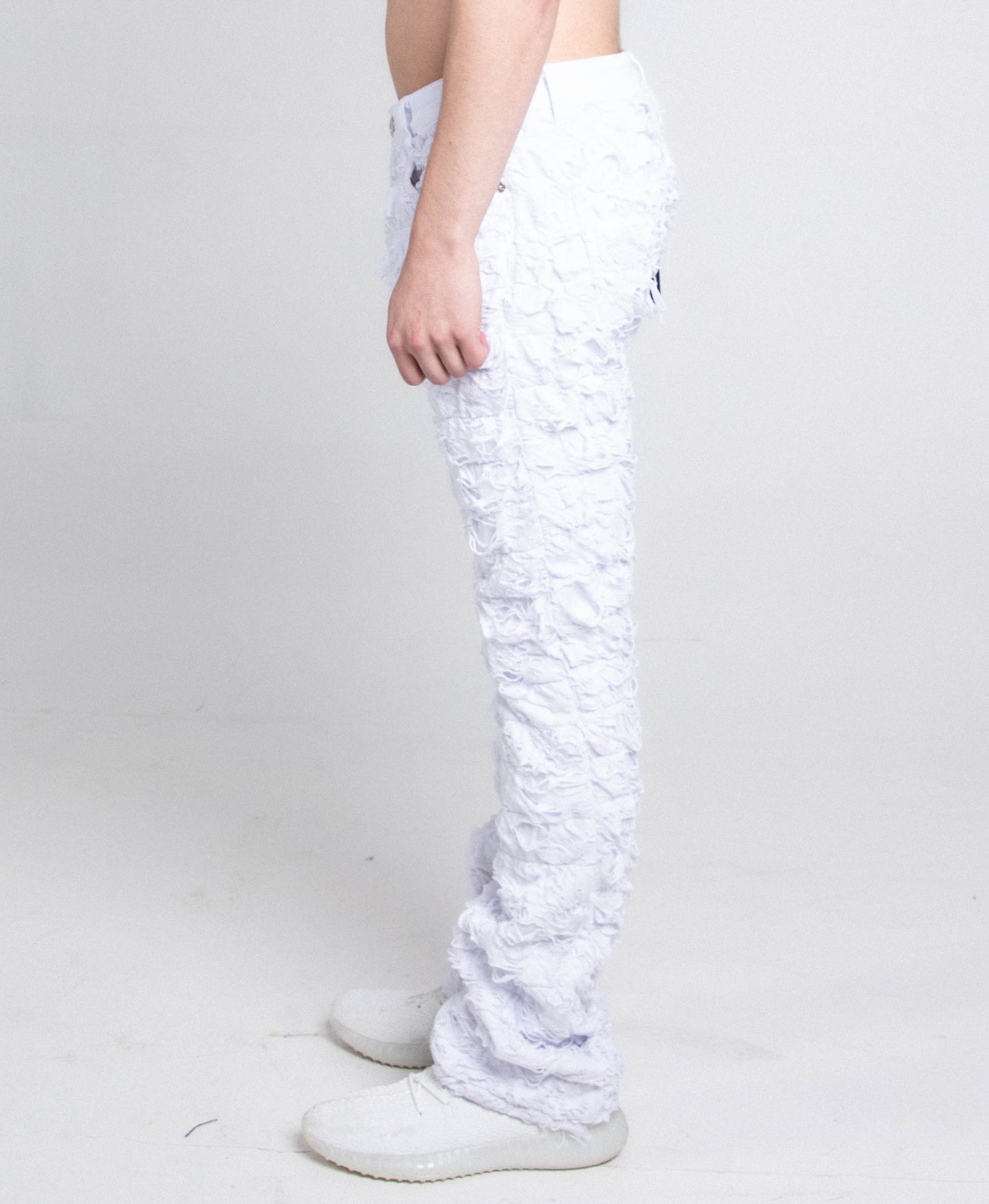 Side view of AR704 WHITE FRAYED STACKED JEANS showcasing ripped stacked legs and mid-rise waist
