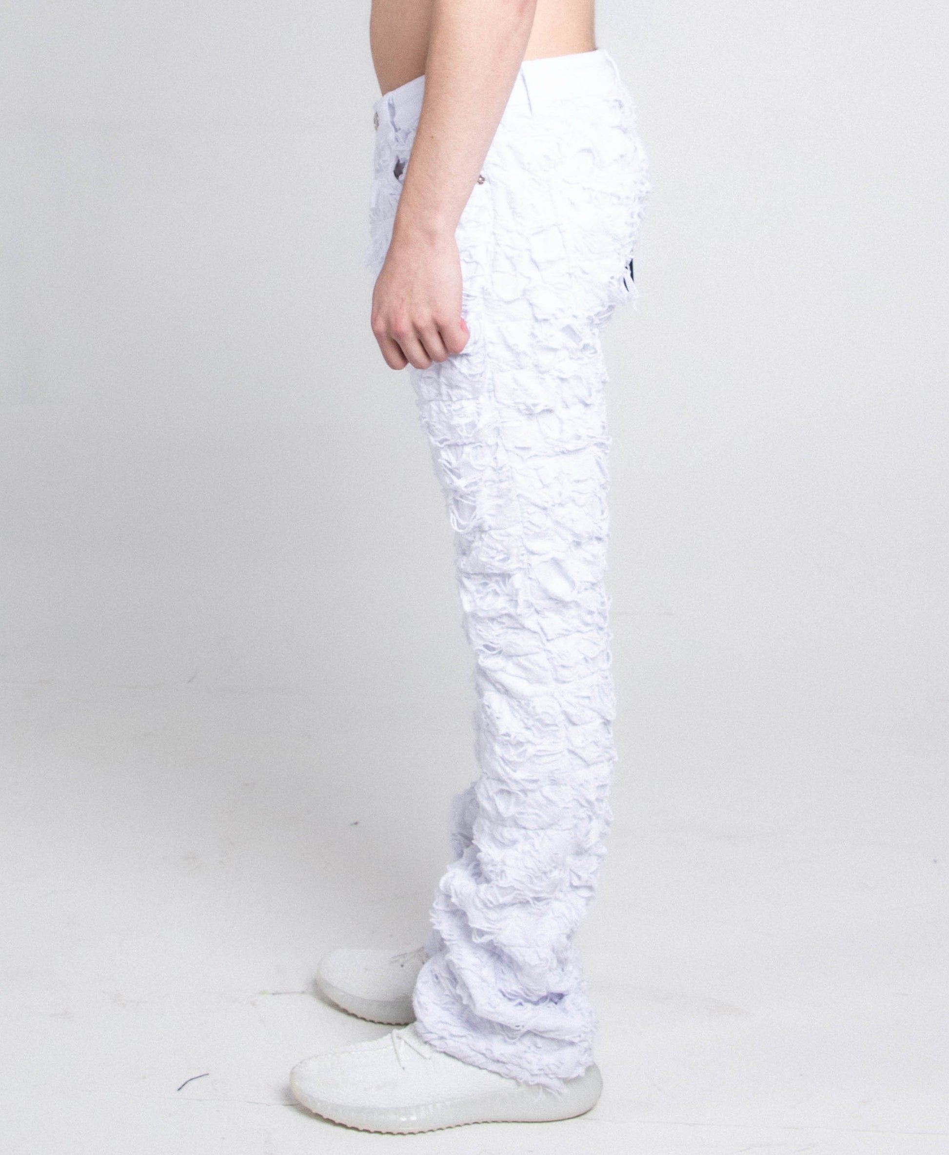 Side view of AR704 WHITE FRAYED STACKED JEANS showcasing ripped stacked legs and mid-rise waist