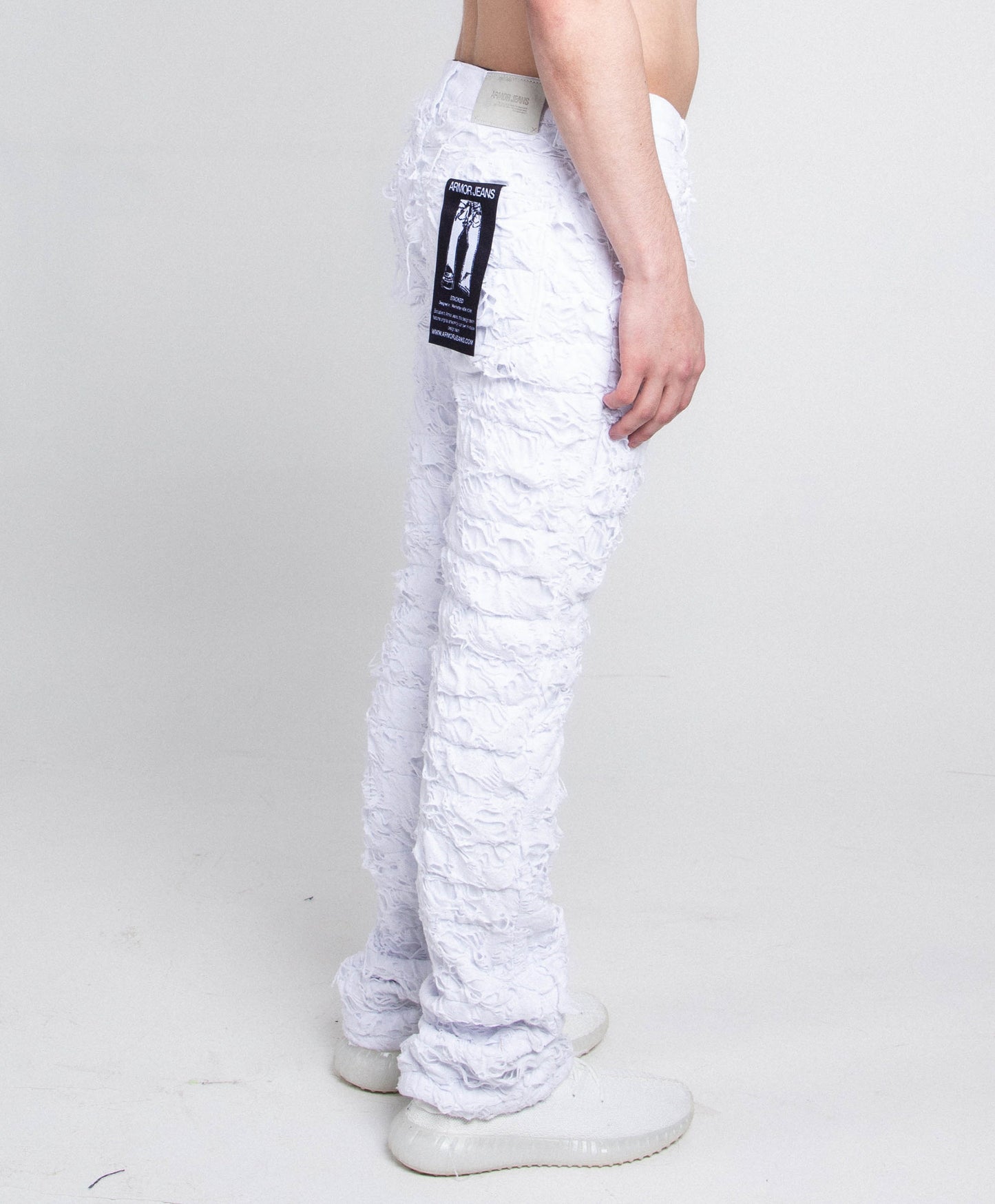 Side view of AR704 WHITE FRAYED STACKED JEANS showcasing frayed detailing and mid-rise stretchy fit with zipper fly and button fastening.