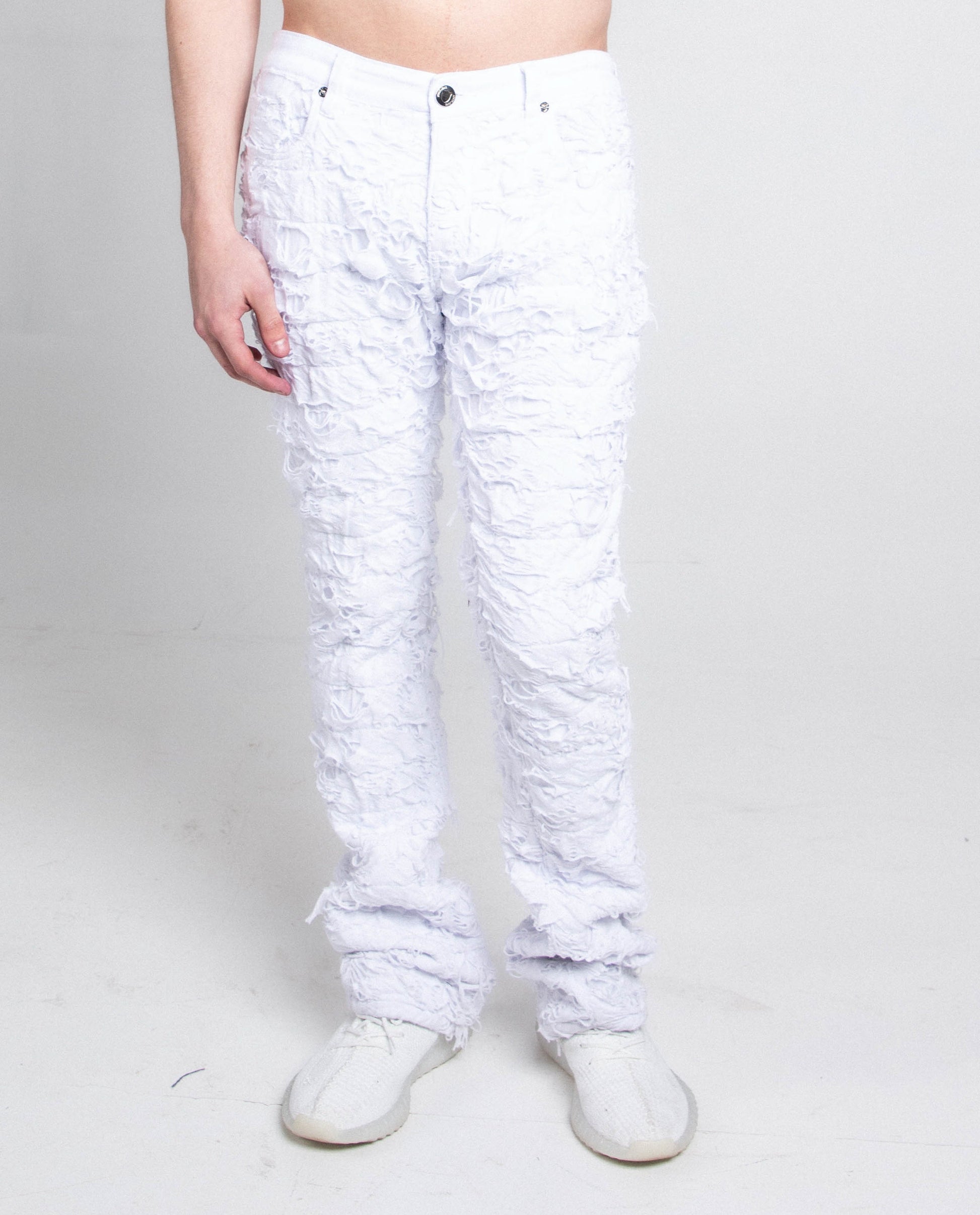 Person wearing AR704 WHITE FRAYED STACKED JEANS with mid-rise waist, stretchy cotton fabric, and ripped stacked design.