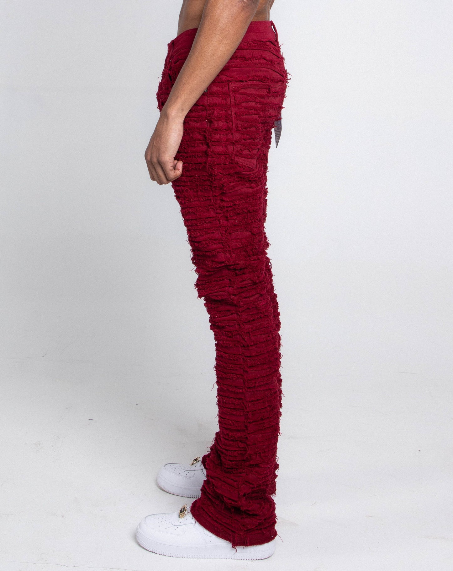 Side view of AJS693 EXTREME FRAYED STACKED JEANS in red with mid-rise waist, stretchy fabric, and extreme frayed inseam detail.