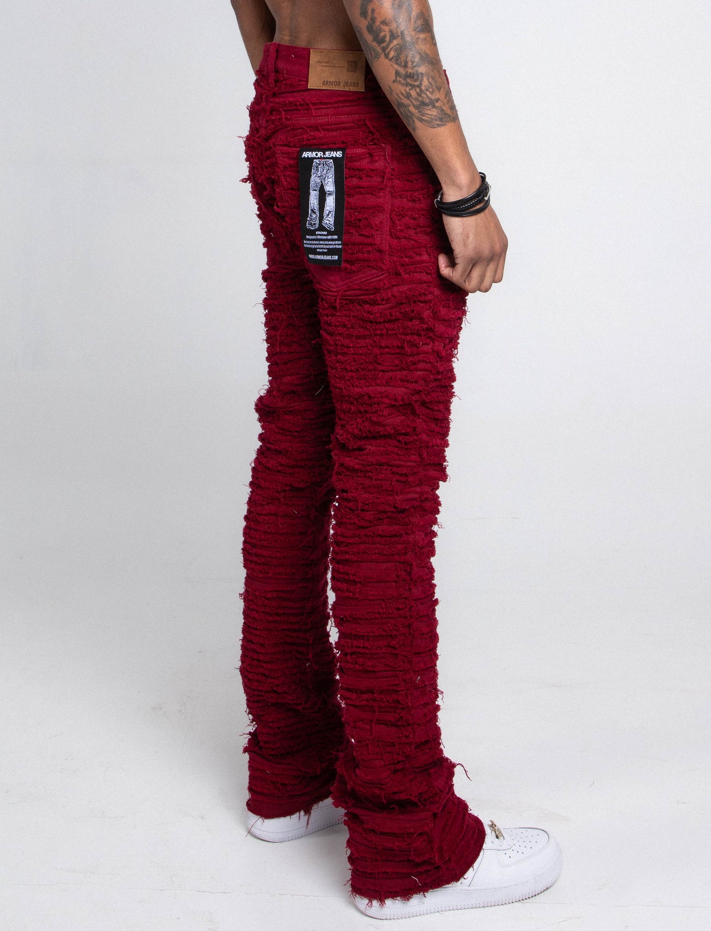 Rear view of a person wearing AJS693 EXTREME FRAYED STACKED JEANS in red, featuring a frayed inseam and stacked leg design, with sneakers.