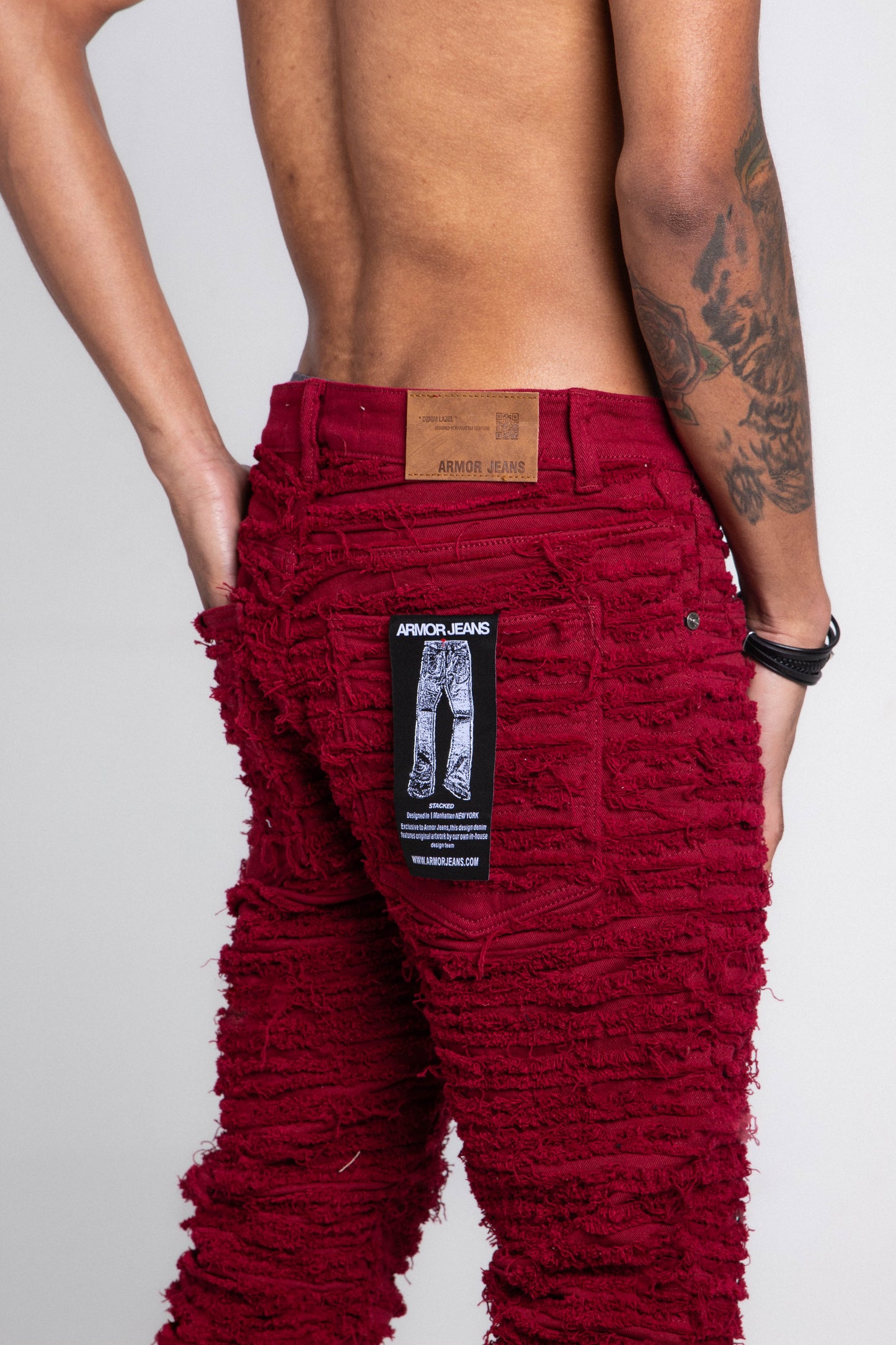 Back view of model wearing AJS693 EXTREME FRAYED STACKED JEANS in red with visible branding and intricate frayed detailing.