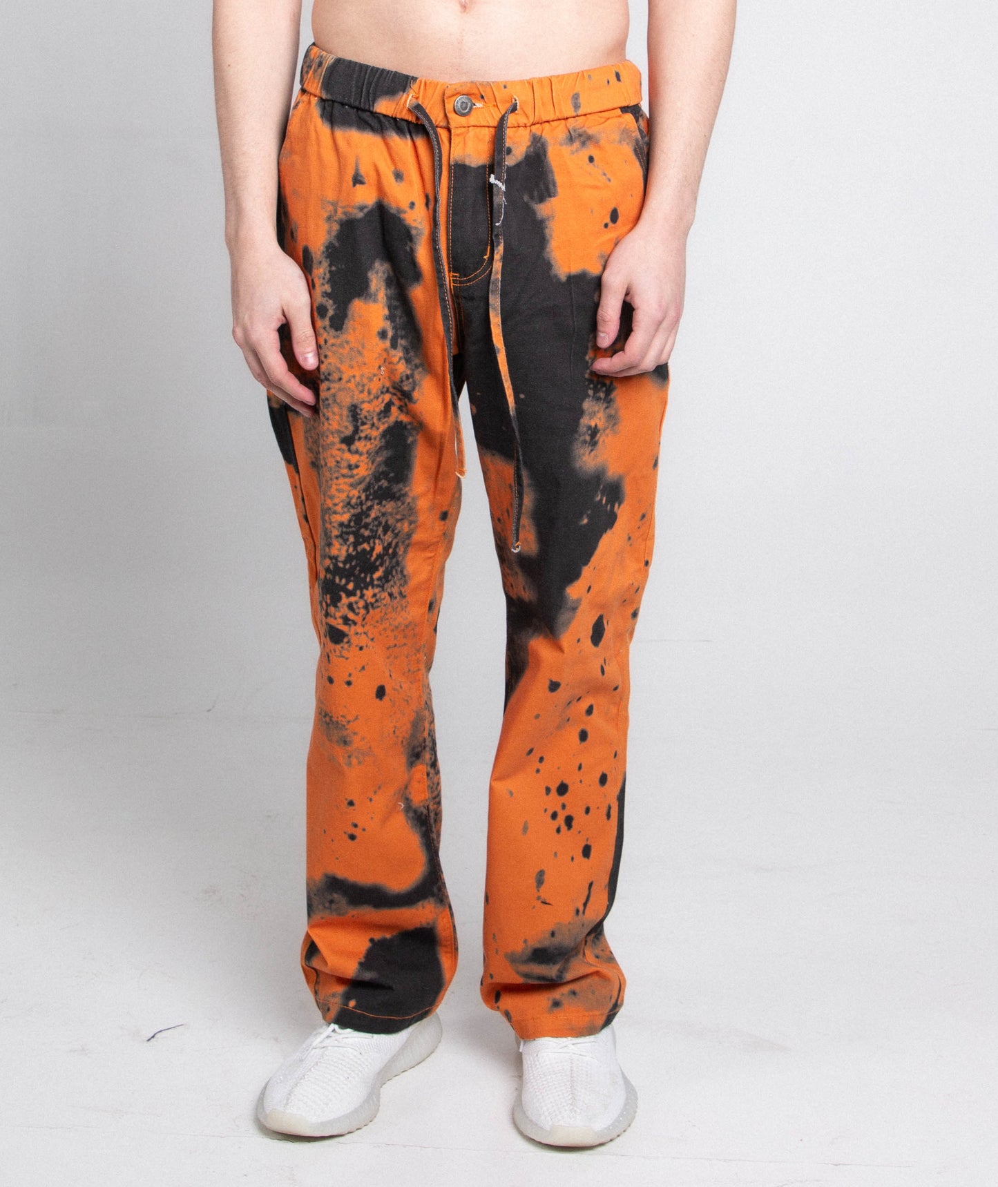 Model wearing AJ04L COLOR DYE LOOSE JEANS with mid-rise waist, black and orange dye pattern, five-pocket design, and elastic band fastening.