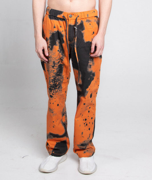 Model wearing AJ04L COLOR DYE LOOSE JEANS with mid-rise waist, black and orange dye pattern, five-pocket design, and elastic band fastening.