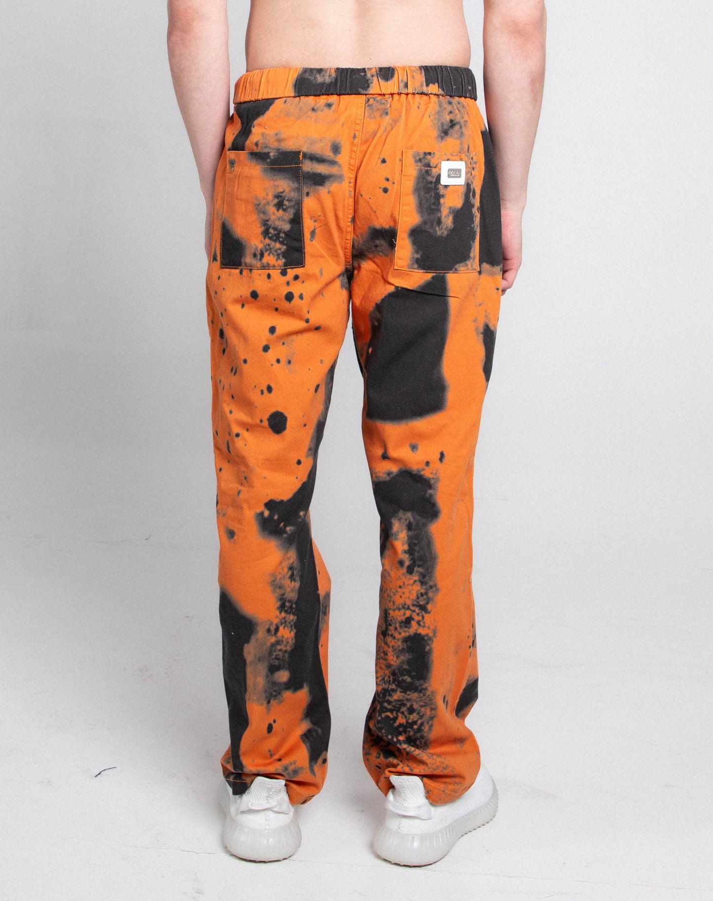 Model wearing AJ04L COLOR DYE LOOSE JEANS with an orange and black dye pattern, showing the back view of the straight-leg mid-rise design.
