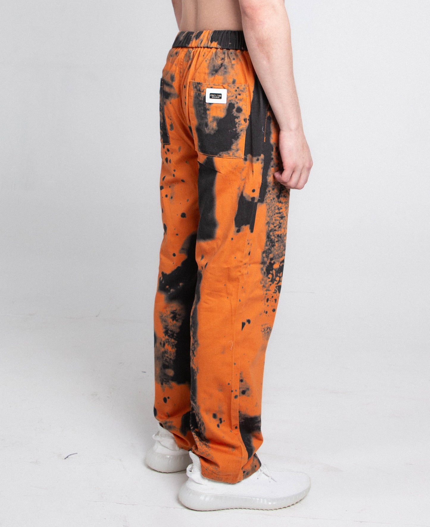 Side view of AJ04L COLOR DYE LOOSE JEANS in orange and black with a mid-rise, straight-leg design and elastic band fastening.