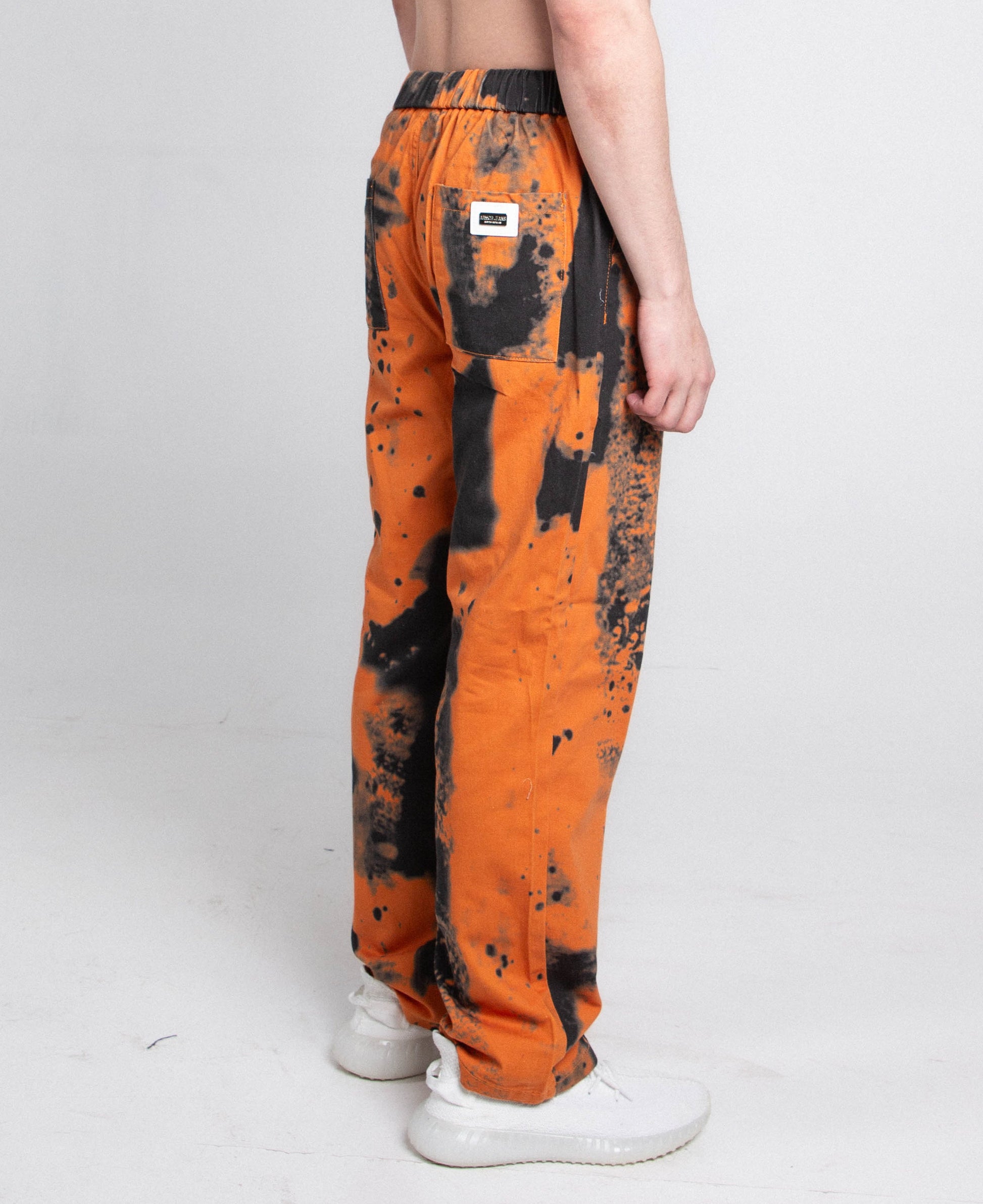 Side view of AJ04L COLOR DYE LOOSE JEANS in orange and black with a mid-rise, straight-leg design and elastic band fastening.