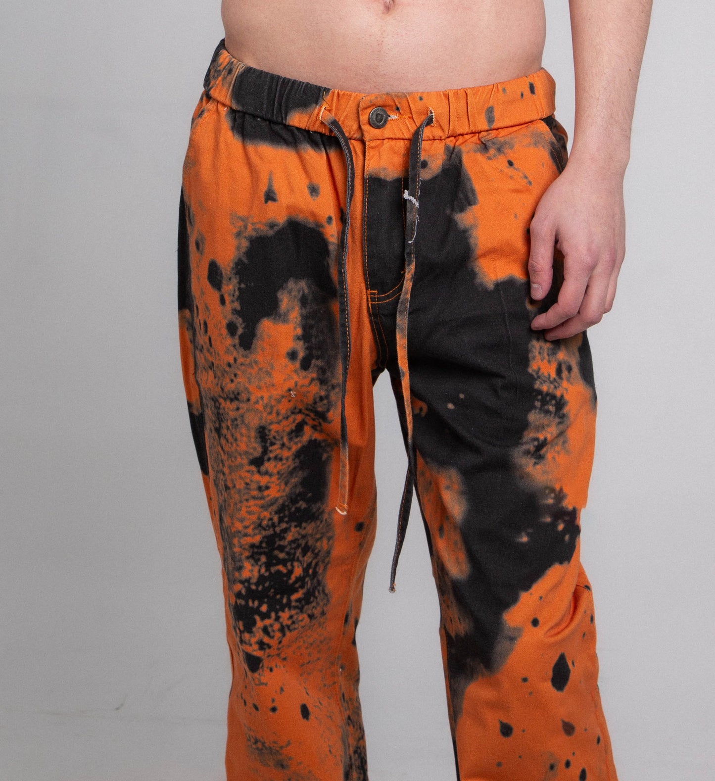 AJ04L COLOR DYE LOOSE JEANS with mid-rise waist, elastic band, and five-pocket design in cotton with orange and black dye pattern.