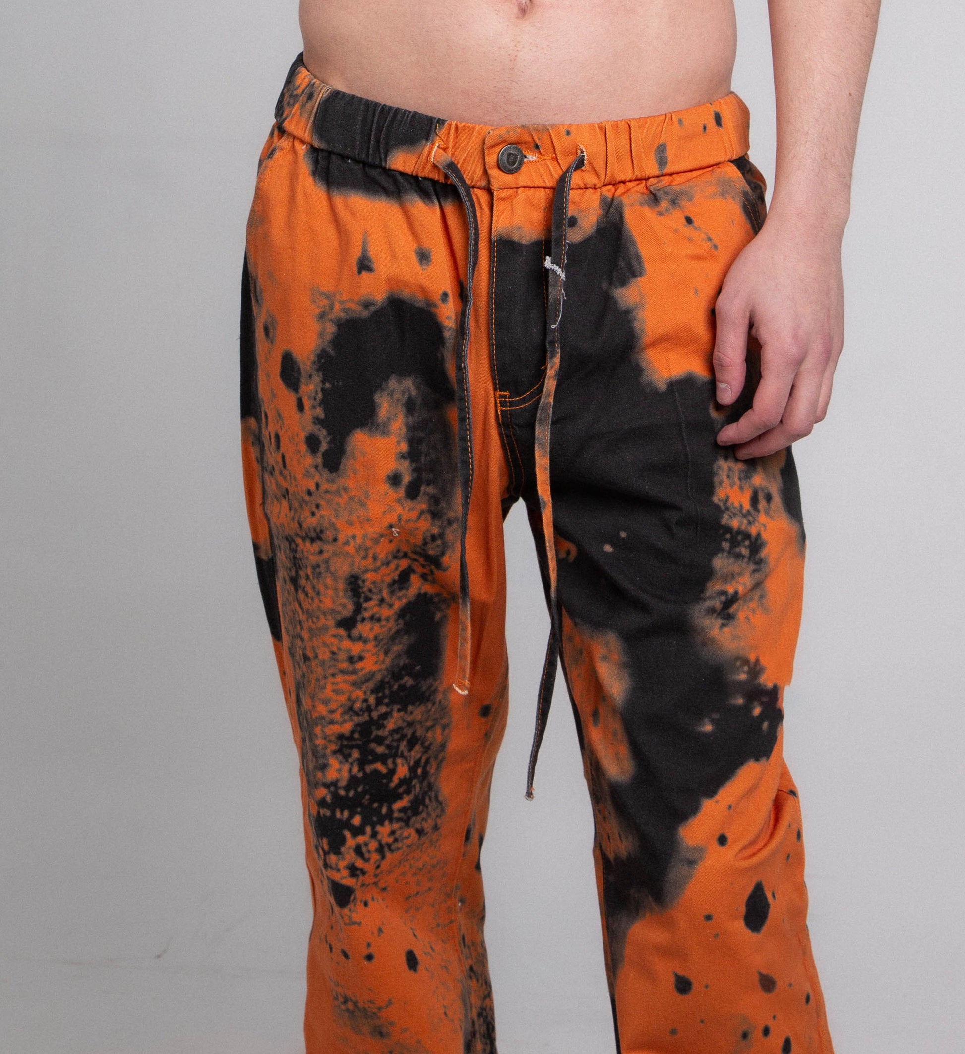 AJ04L COLOR DYE LOOSE JEANS with mid-rise waist, elastic band, and five-pocket design in cotton with orange and black dye pattern.