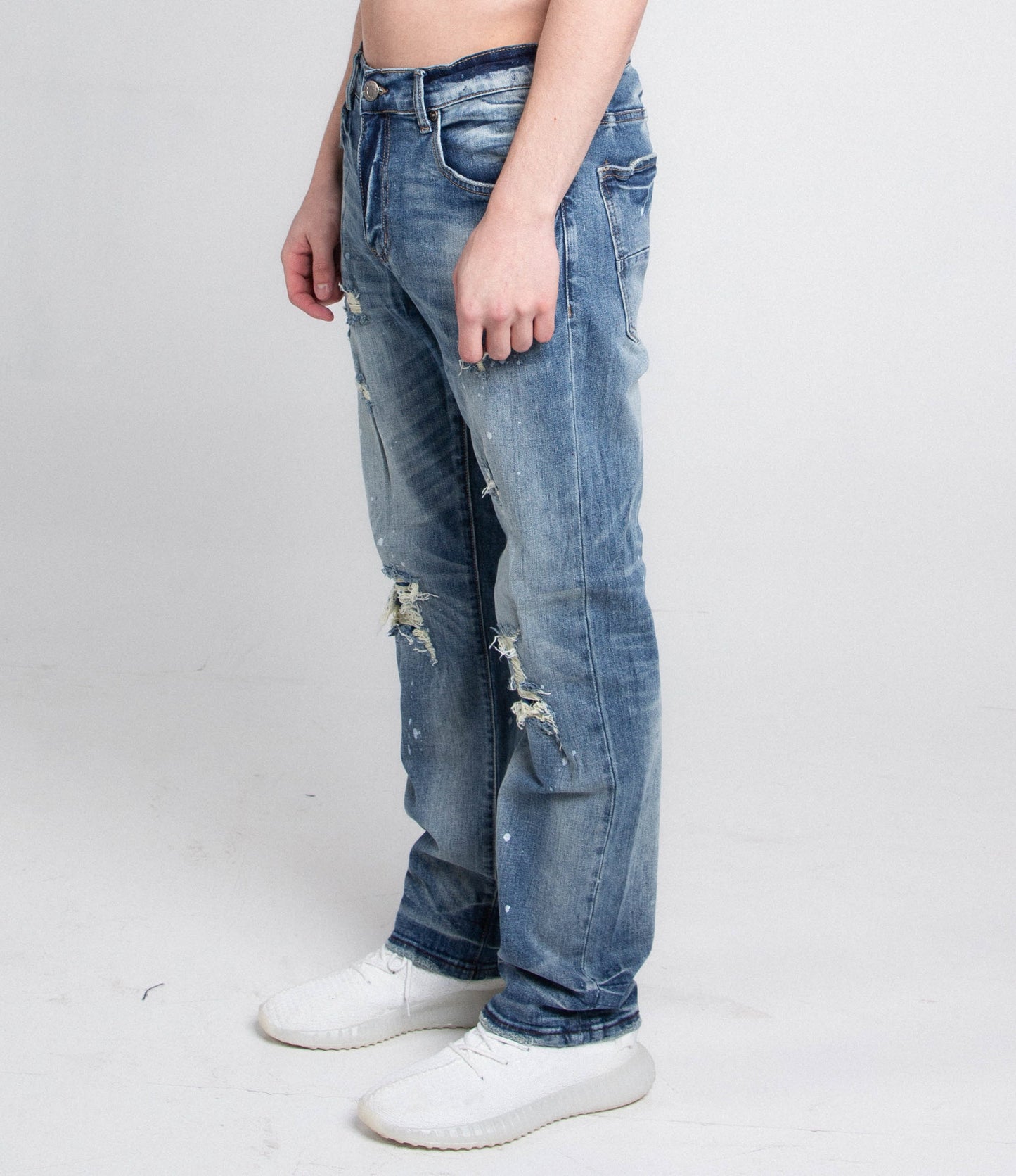 Side view of AJ05C CASUAL SKINNY DISTRESSED JEANS, mid rise, five pockets, belt loops, and zipper fly, worn with white shoes.