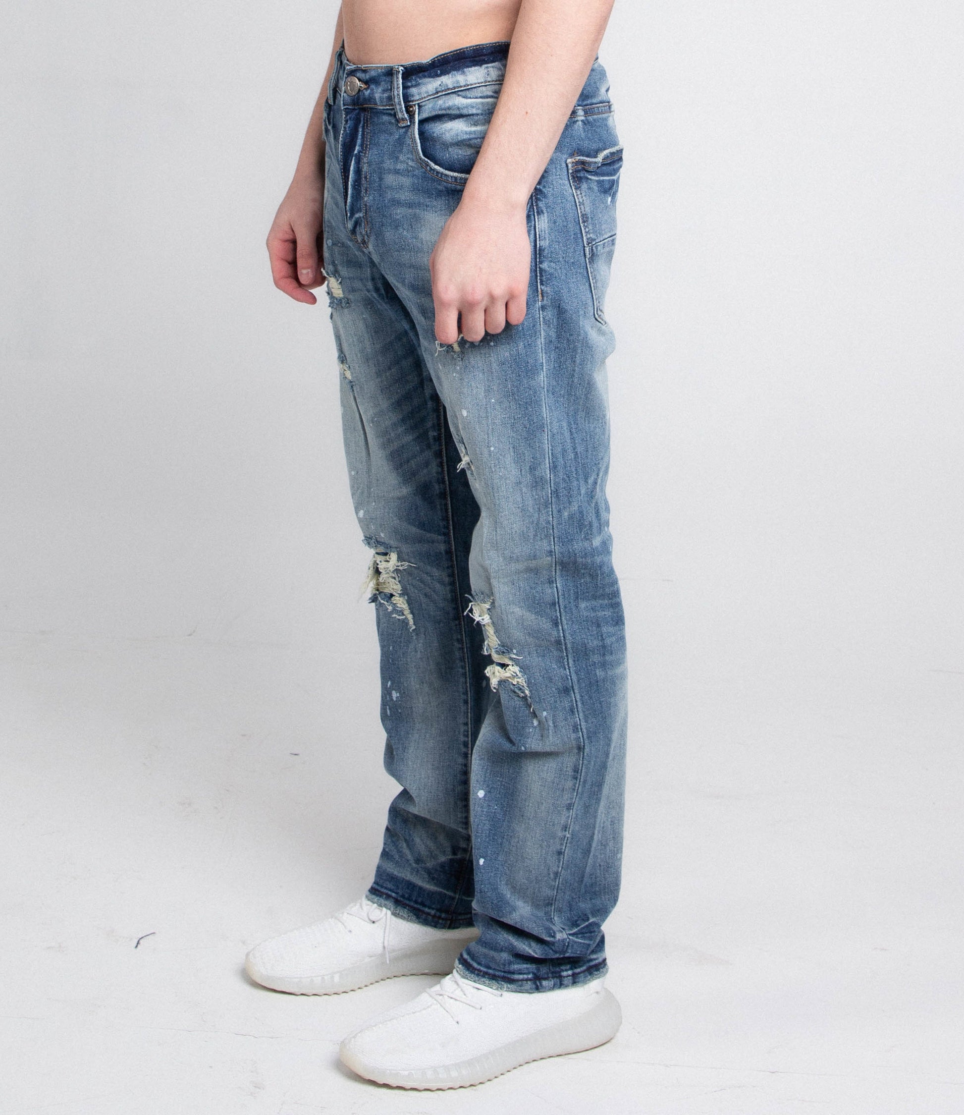 Side view of AJ05C CASUAL SKINNY DISTRESSED JEANS, mid rise, five pockets, belt loops, and zipper fly, worn with white shoes.