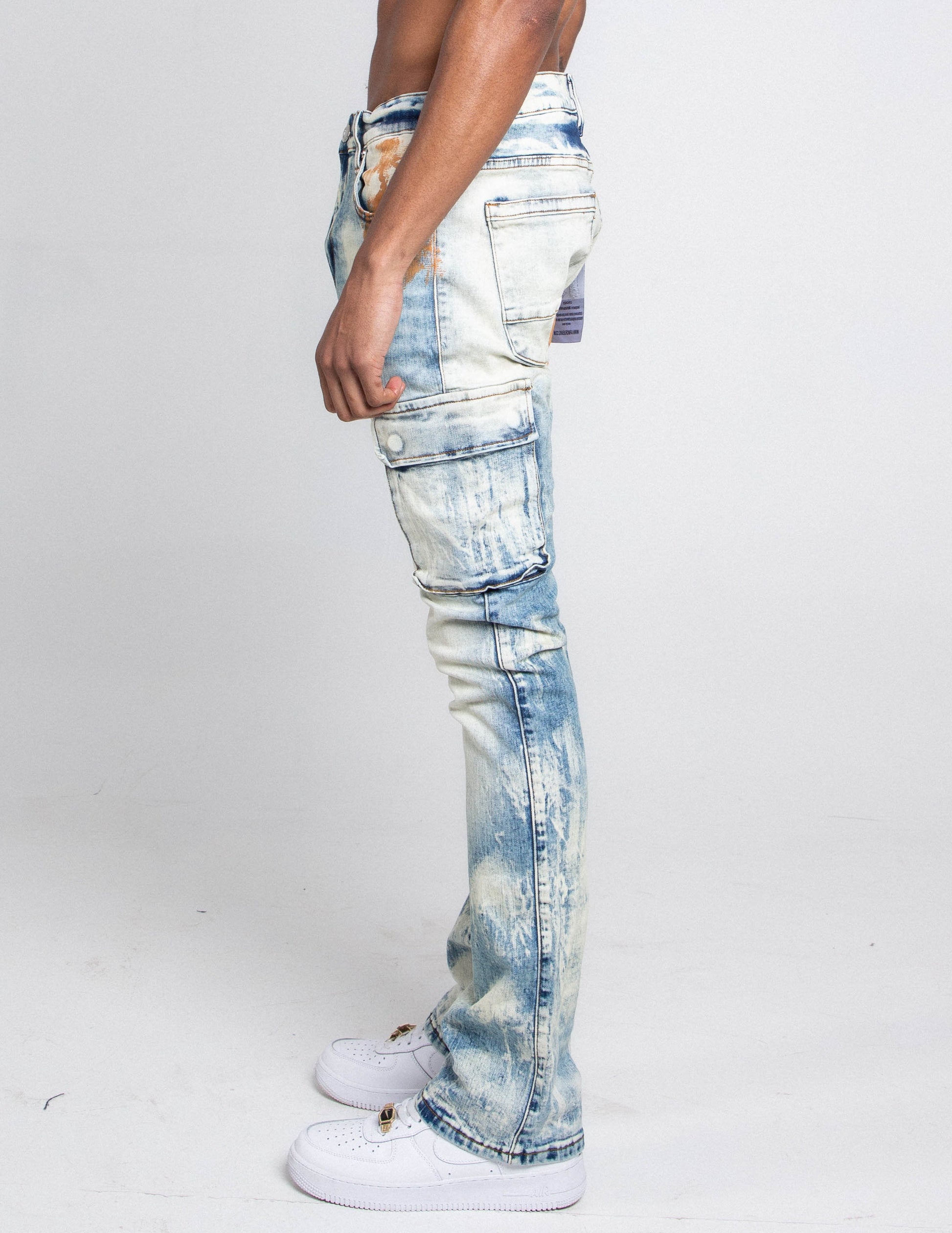 Side view of AJ29SK GREY/WHITE WASH STACKED CARGO JEANS with splash paint design and cargo pockets, modeled by a person.