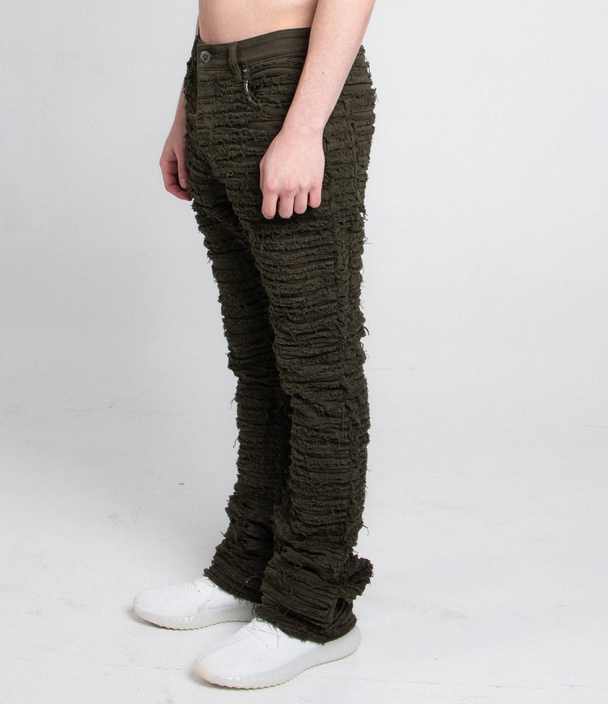 Man wearing AJS693 EXTREME FRAYED STACKED JEANS with mid-rise waist, stretchy fabric, frayed inseams, and stacked leg design.