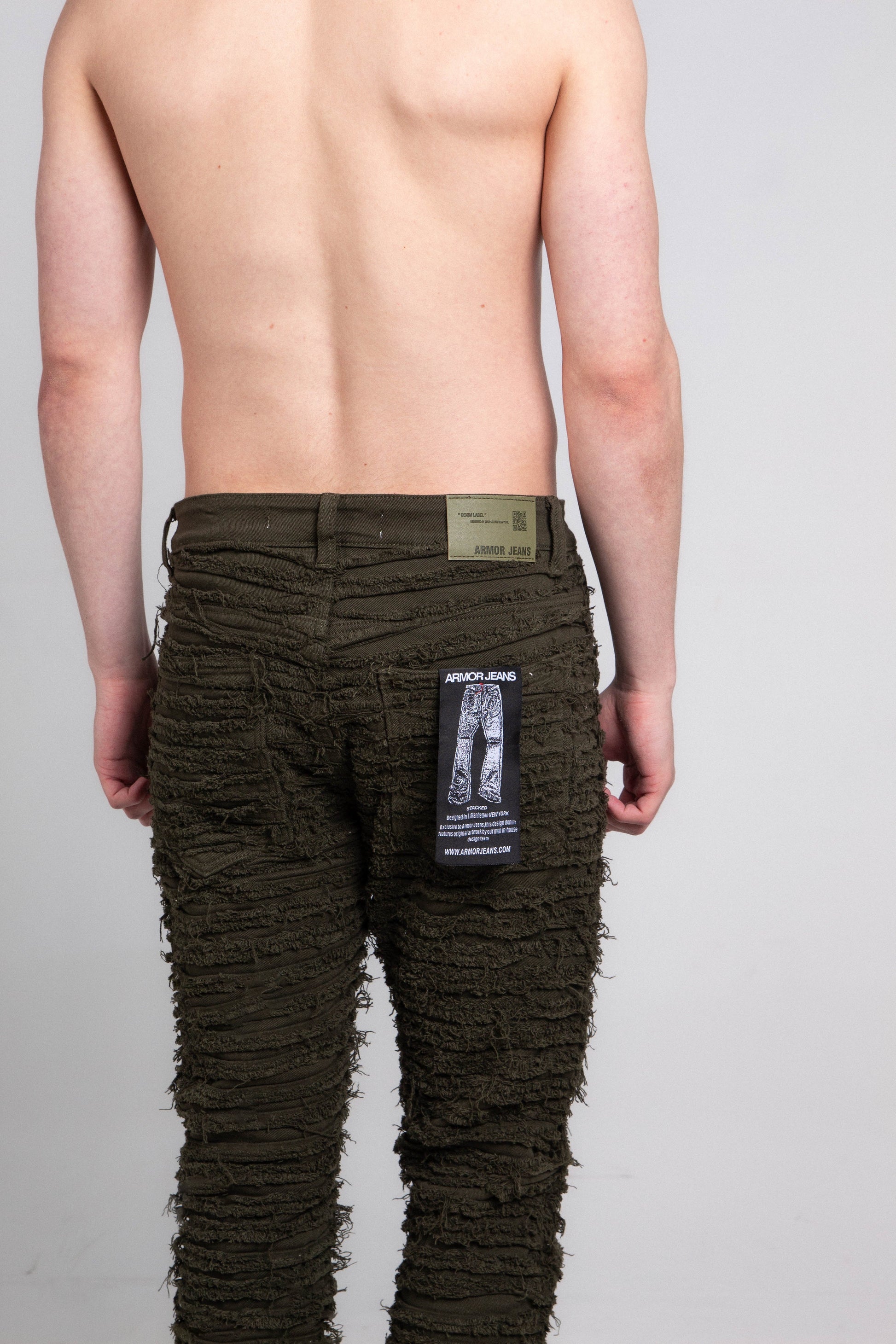 Back view of AJS693 EXTREME FRAYED STACKED JEANS showcasing frayed design and logo tag on a male model, mid-rise, stretchy fabric.