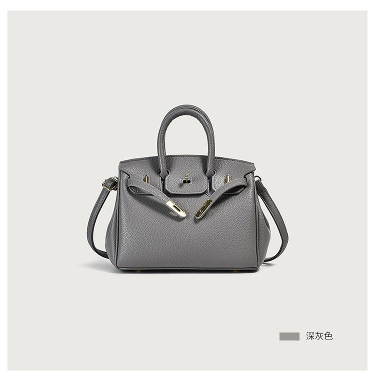 Gray handbag with handles and strap, showcasing a sleek and minimalist design on a neutral background.